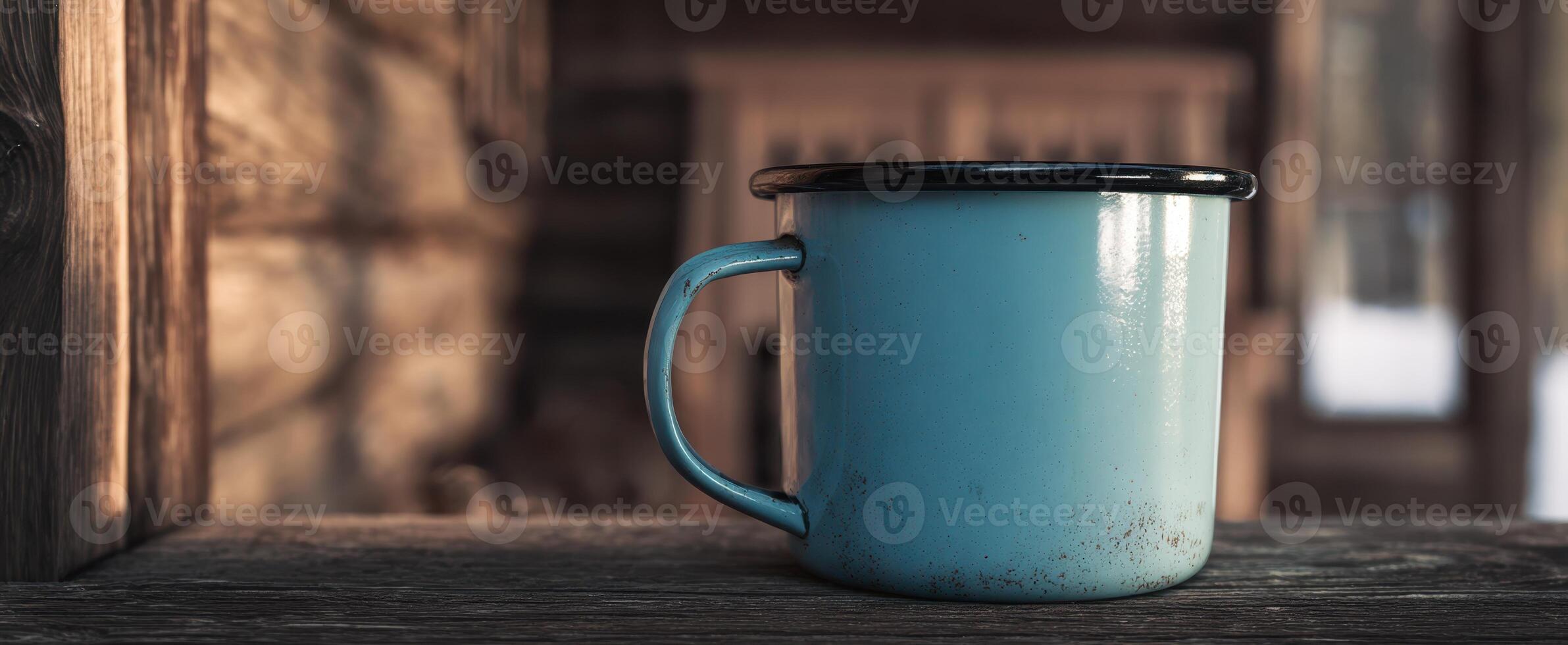 The rustic blue enamel cup resting on a wooden table in a cozy cabin setting photo