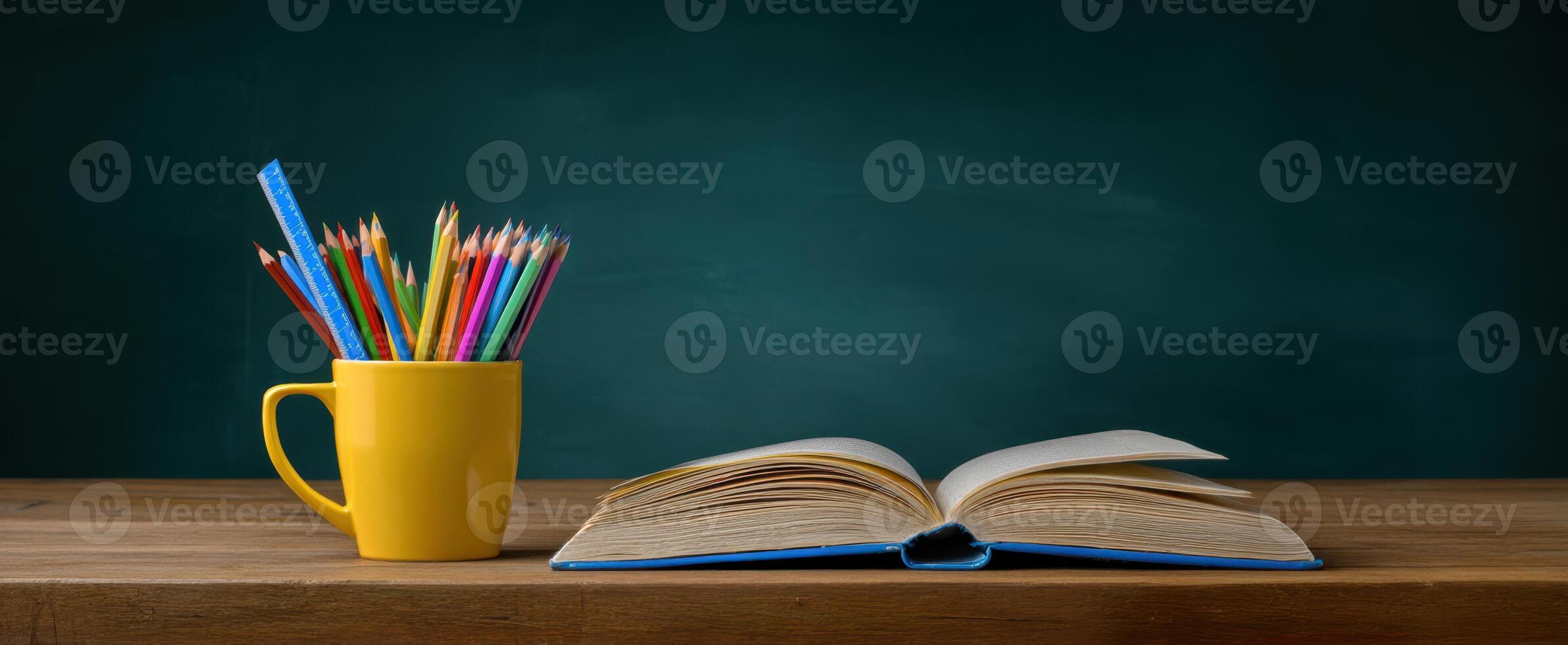The open book and colorful pencils on a wooden desk background. photo
