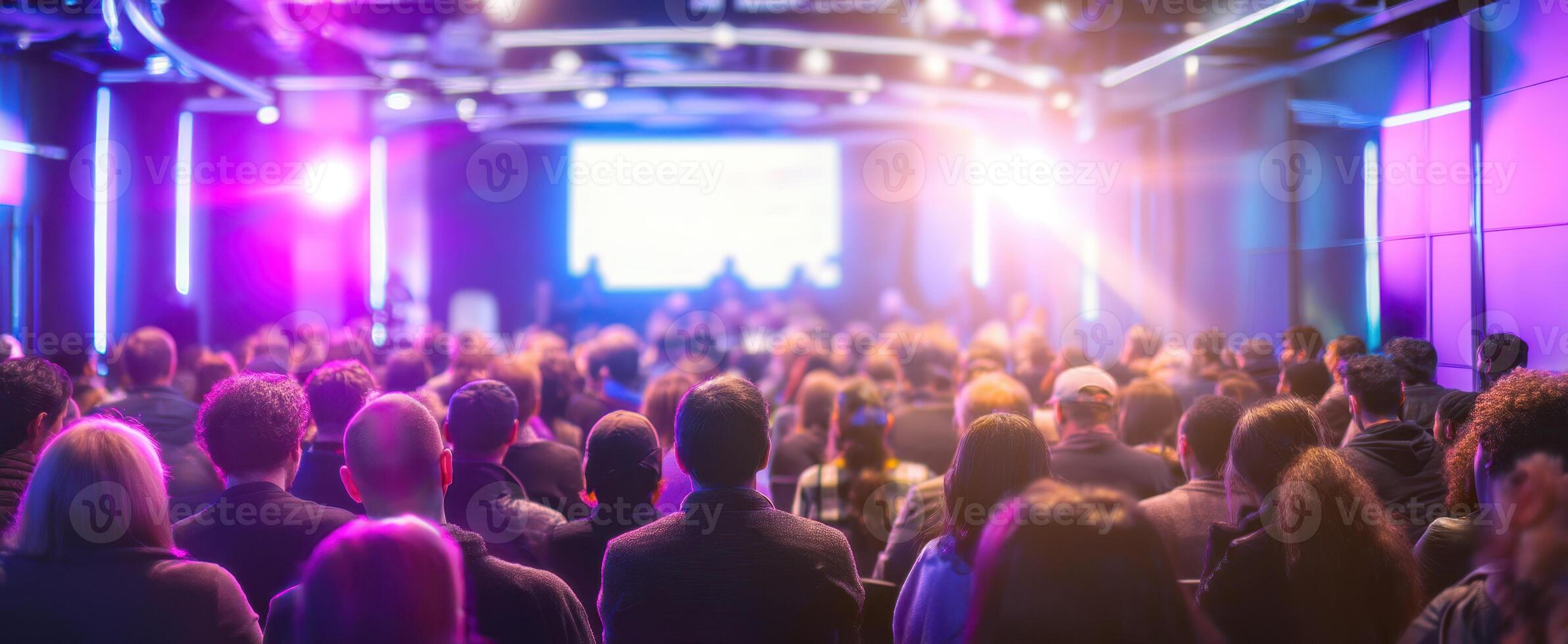 The engaging audience at a modern conference with vibrant lighting and discussions. photo