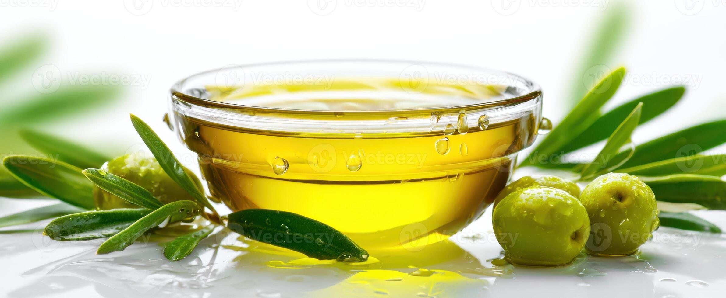 The olive oil in a glass bowl surrounded by fresh leaves and olives. photo