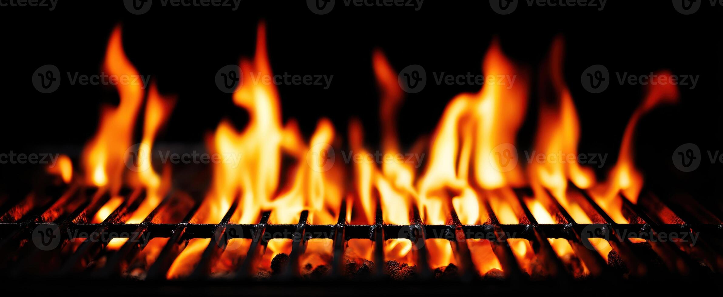 The intense flames dancing over a grill in a darkened environment. photo