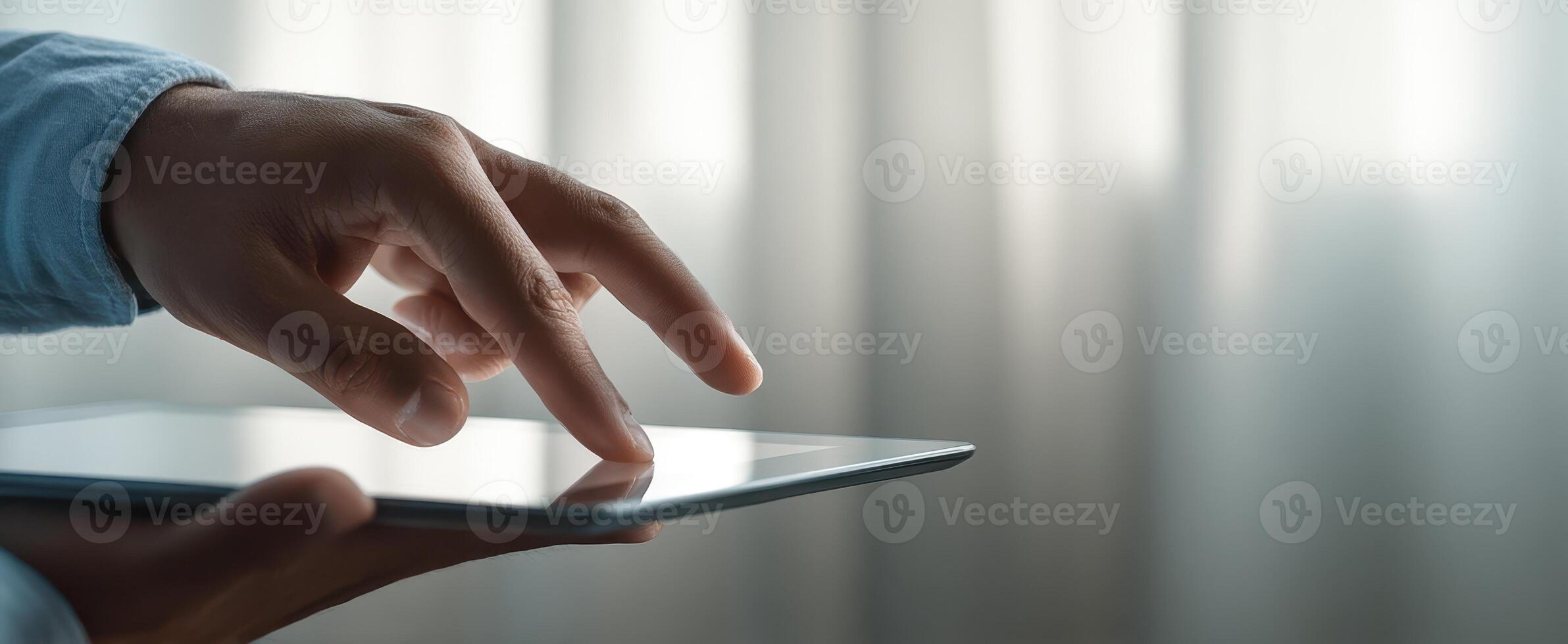 The hand interacting with a tablet against a softly lit background. photo