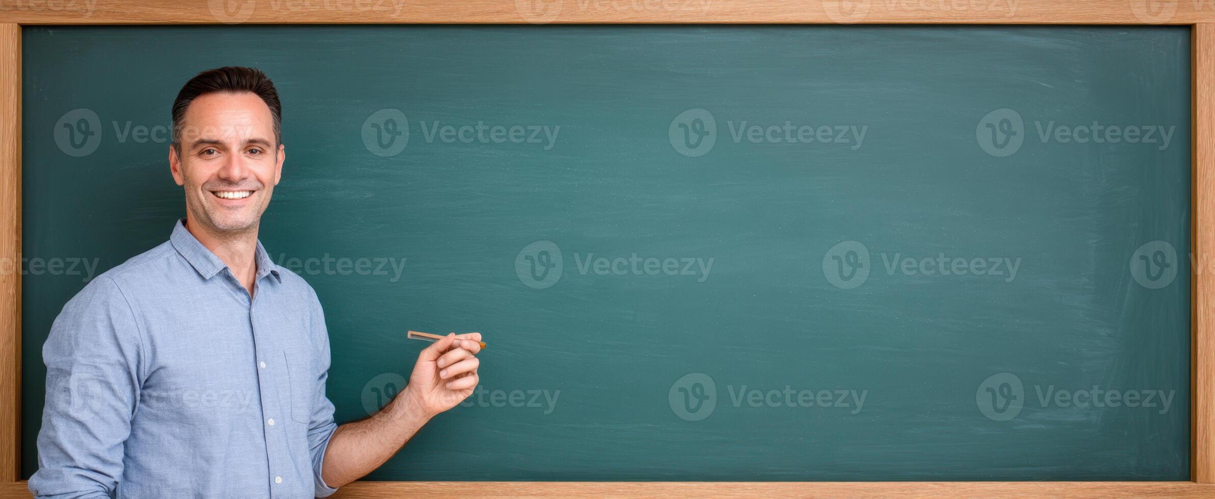 The smiling teacher presenting in front of a blank chalkboard for education. photo
