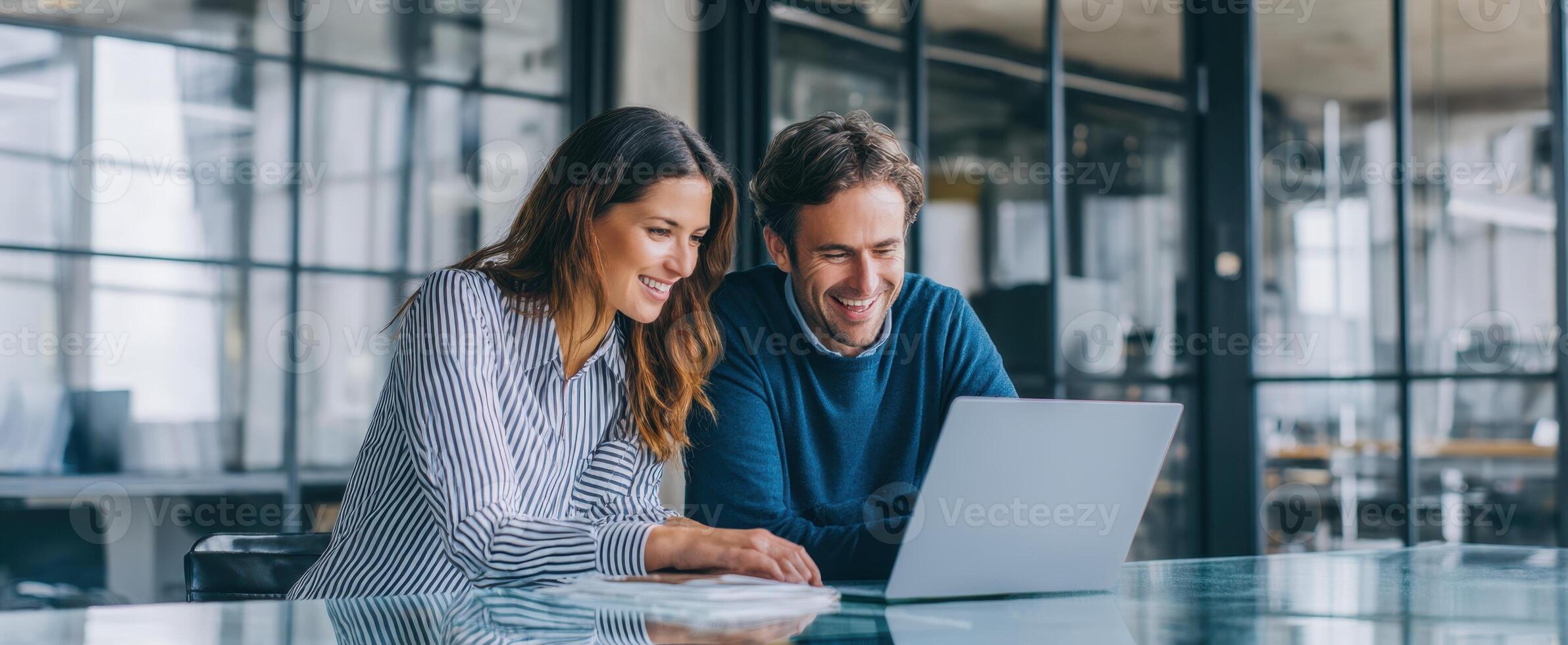 The young professionals collaborating over a laptop in a modern office space. photo