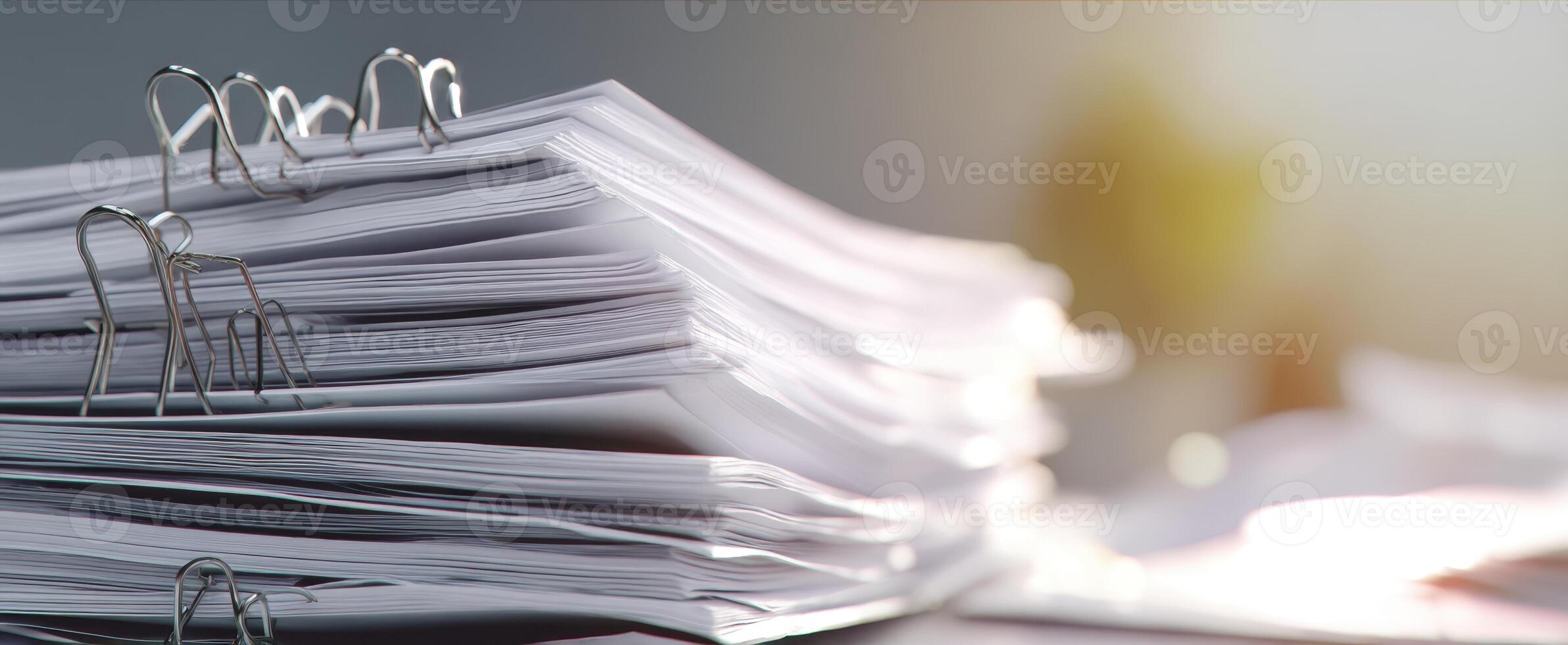 The stack of organized documents with binder clips on a workspace desk. photo