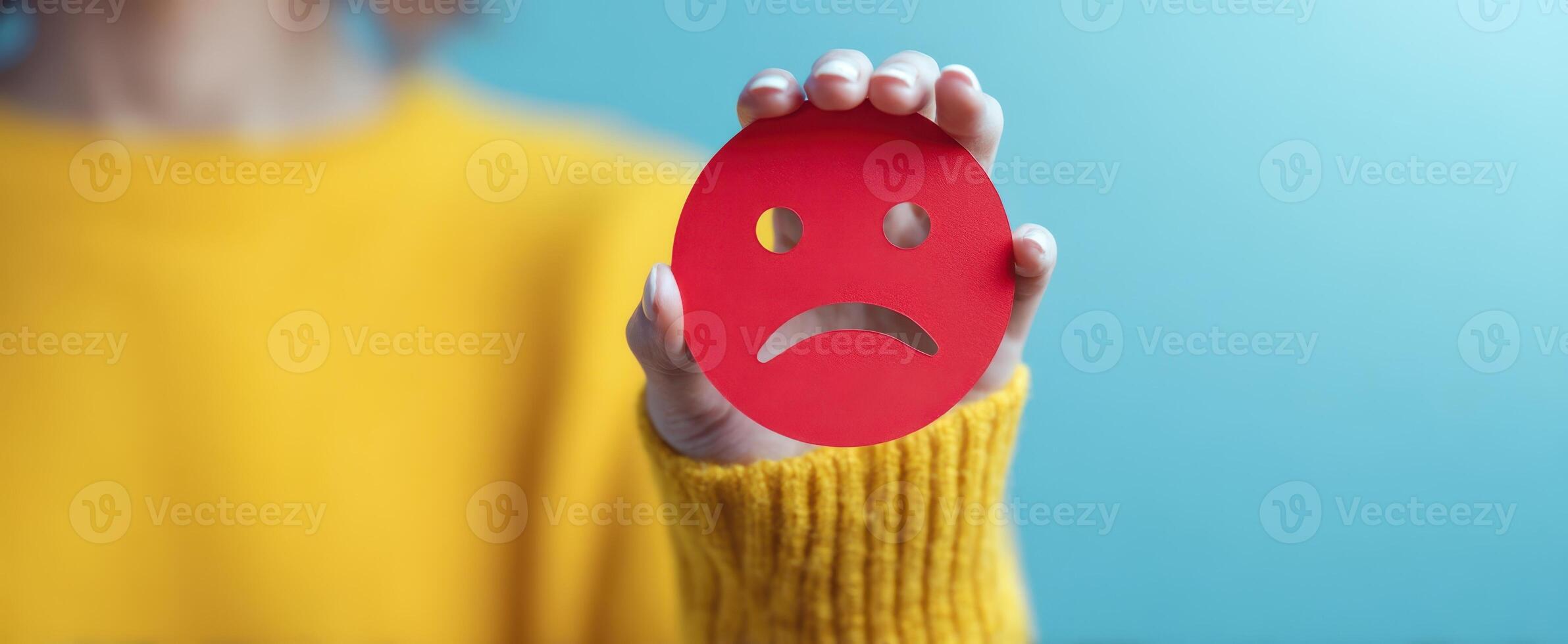 The red sad face held by a person expressing negative emotions. photo