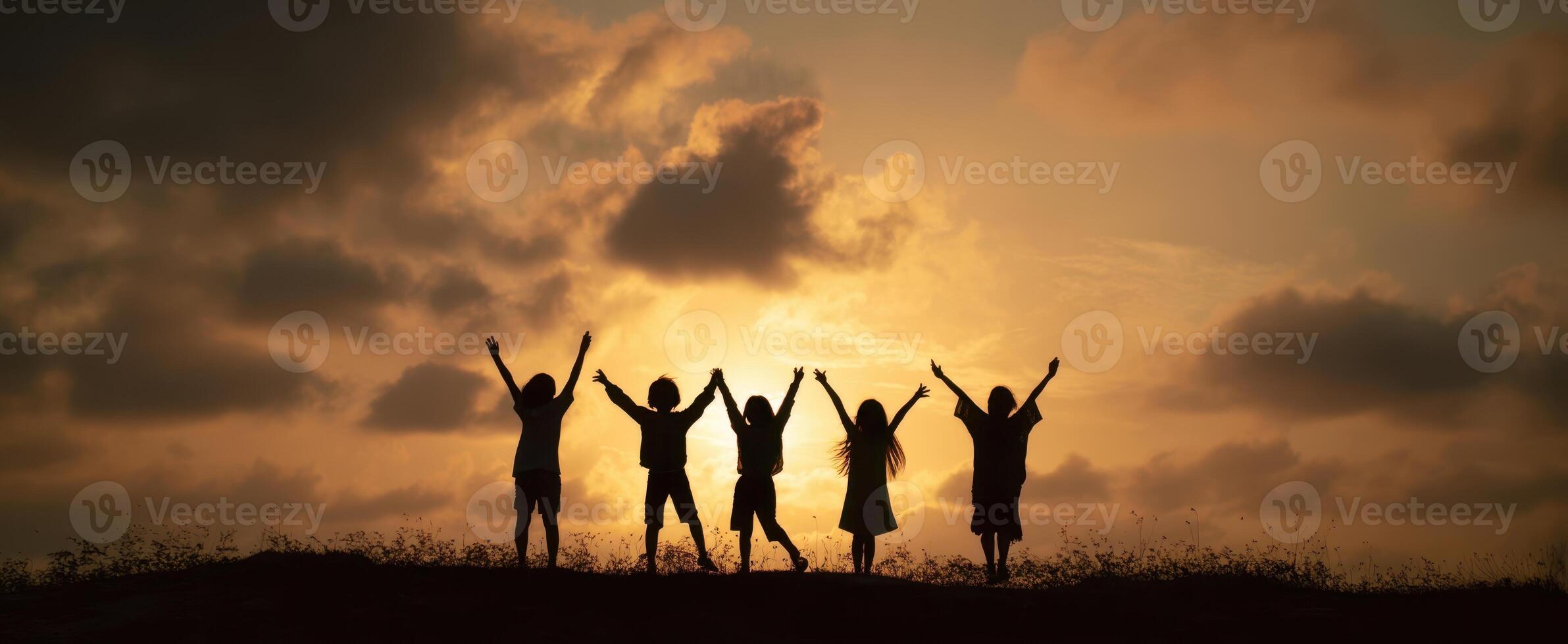 The joyful silhouettes of children celebrating together at sunset. photo