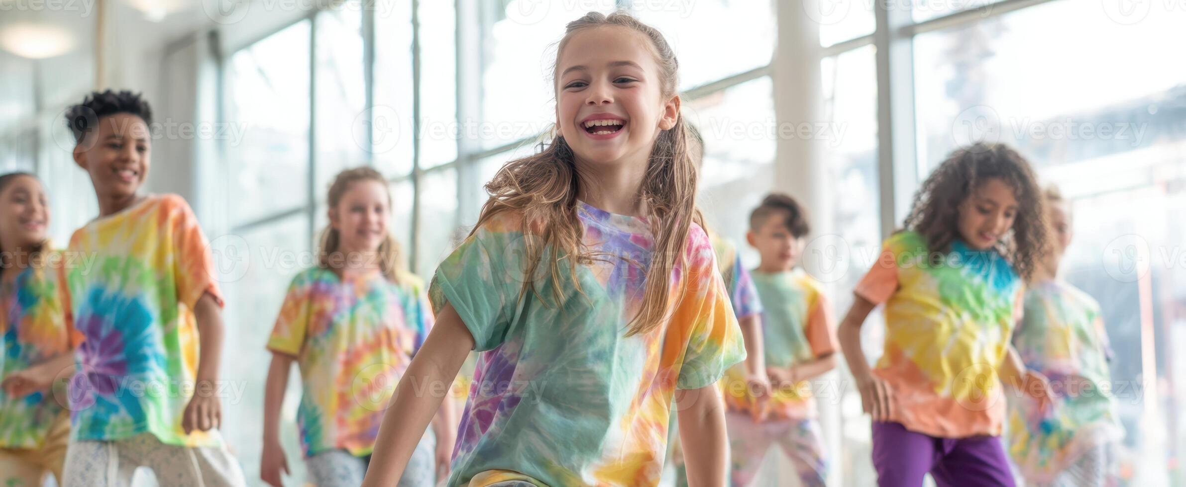 The joyful children dancing together in colorful tie-dye shirts. photo