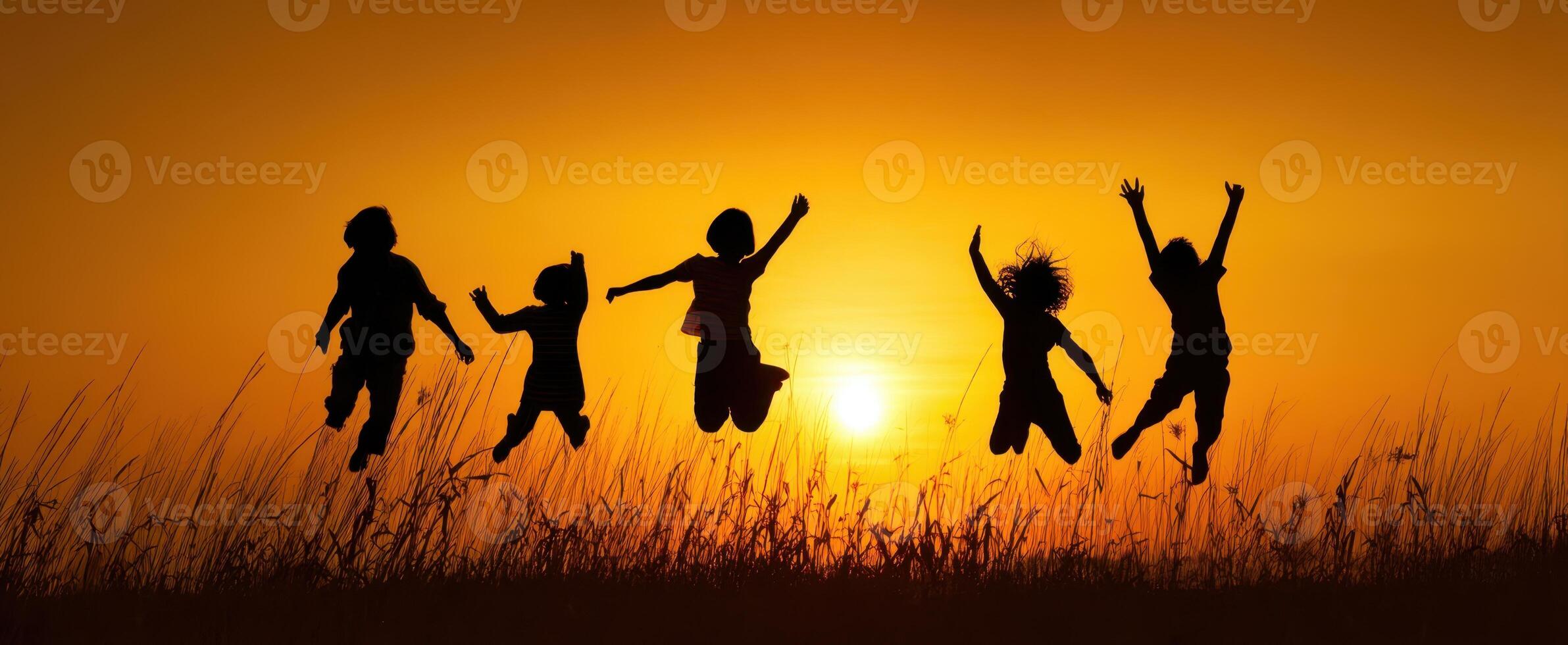 The joyful children jumping in silhouette against a vibrant sunset background. photo