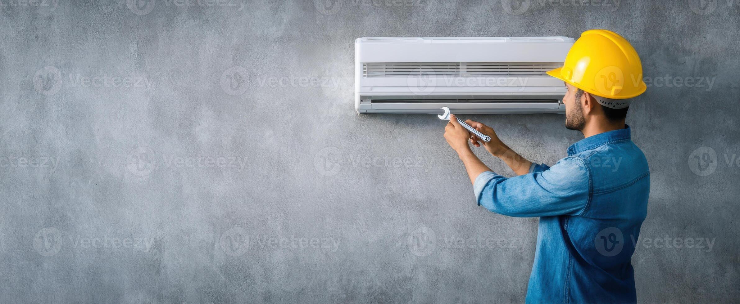 The technician is installing an air-conditioning unit on a concrete wall. photo