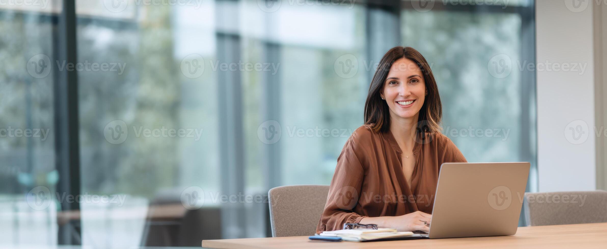 The smiling woman working at her laptop in a modern office setting. photo