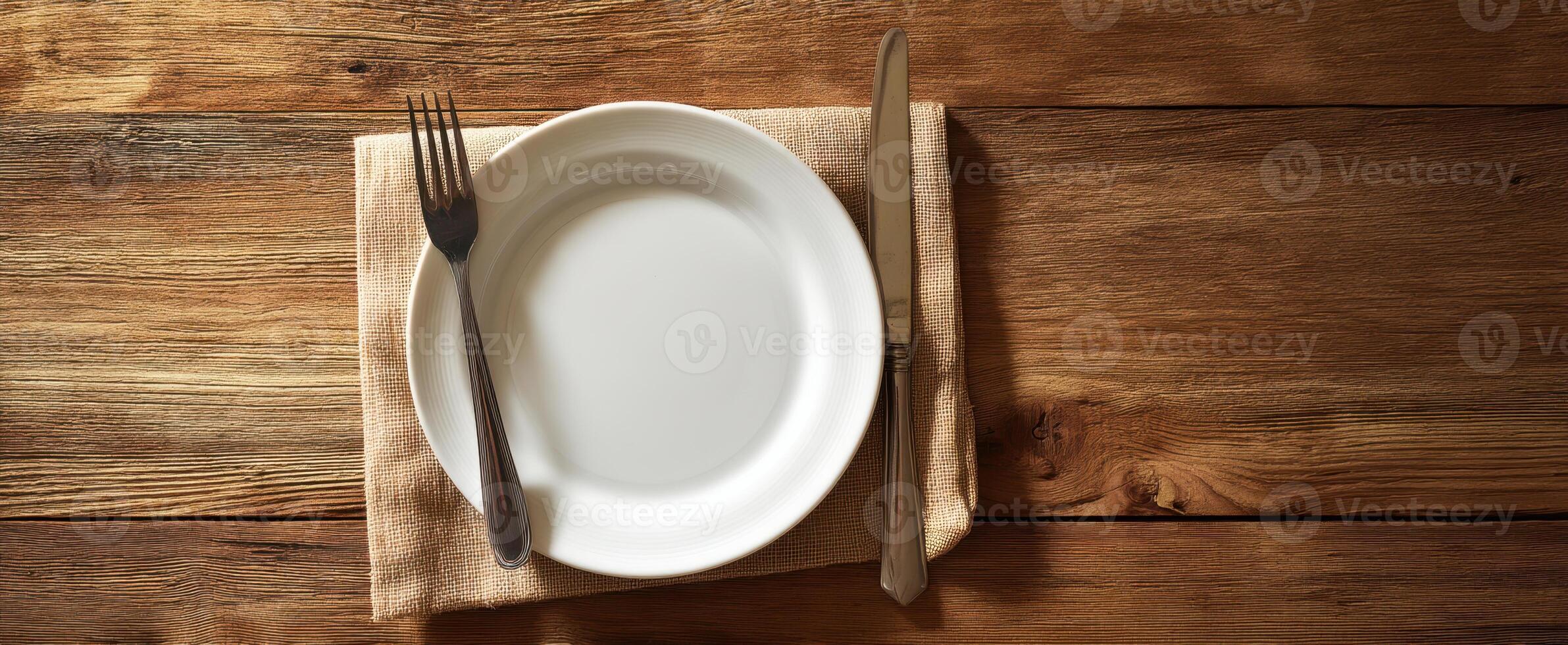 The elegant table setting with a white plate and cutlery on a wooden surface. photo
