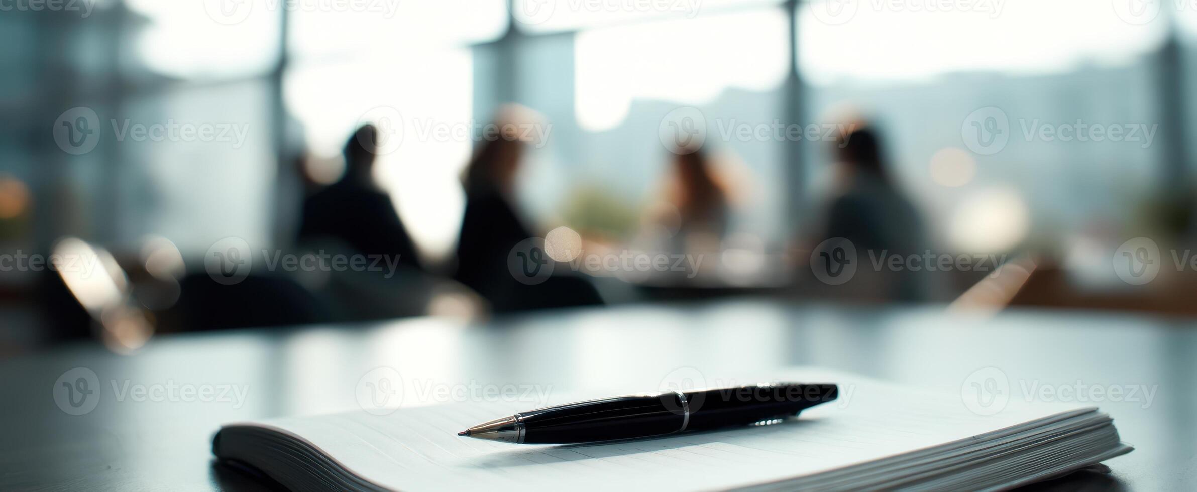 The pen resting on a notebook during a collaborative business meeting photo