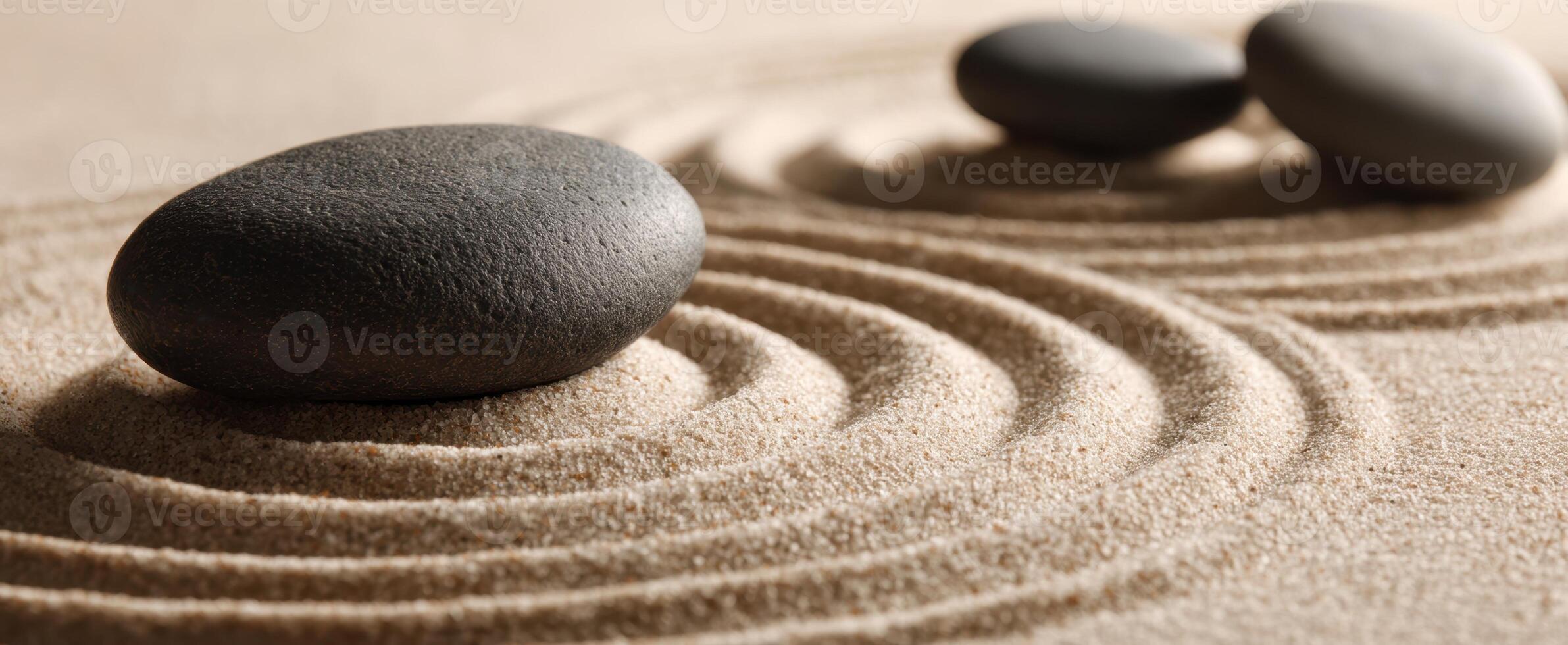 The serene black stones resting gently on smooth sand patterns photo