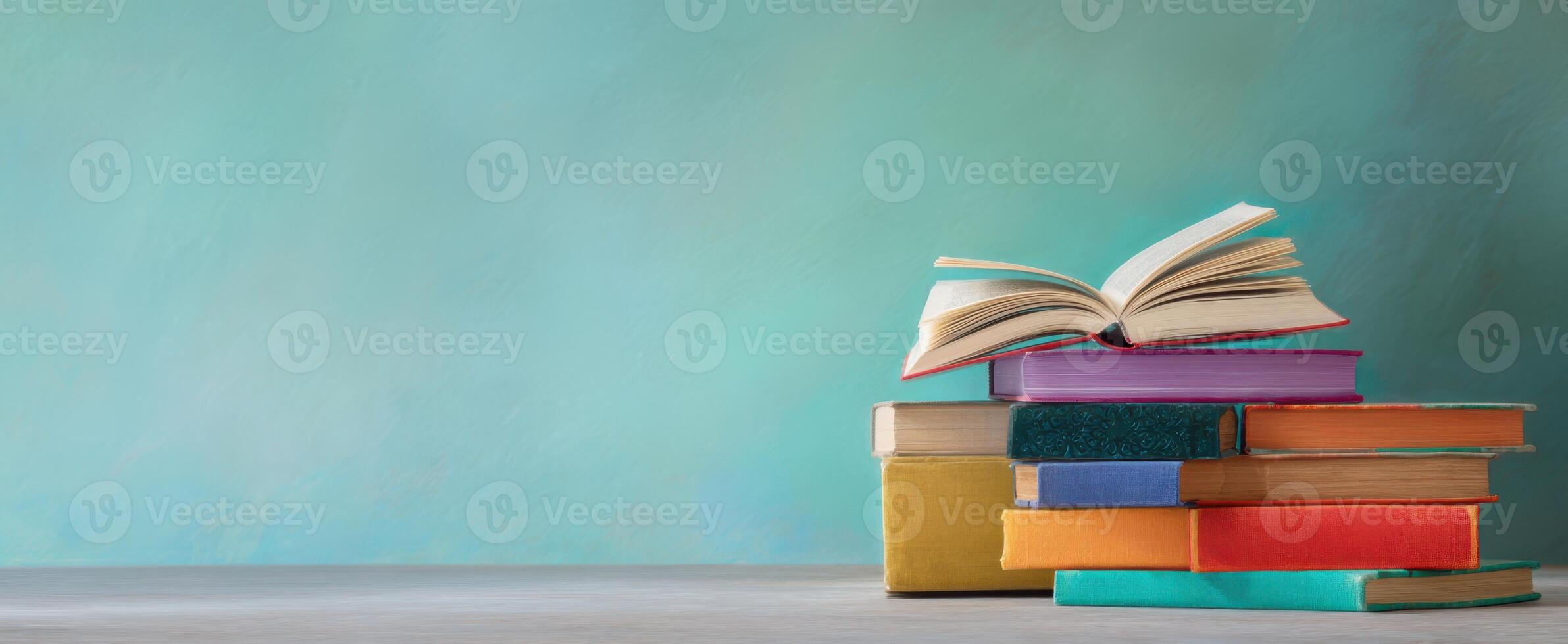 The vibrant stack of books with an open book in a serene setting. photo