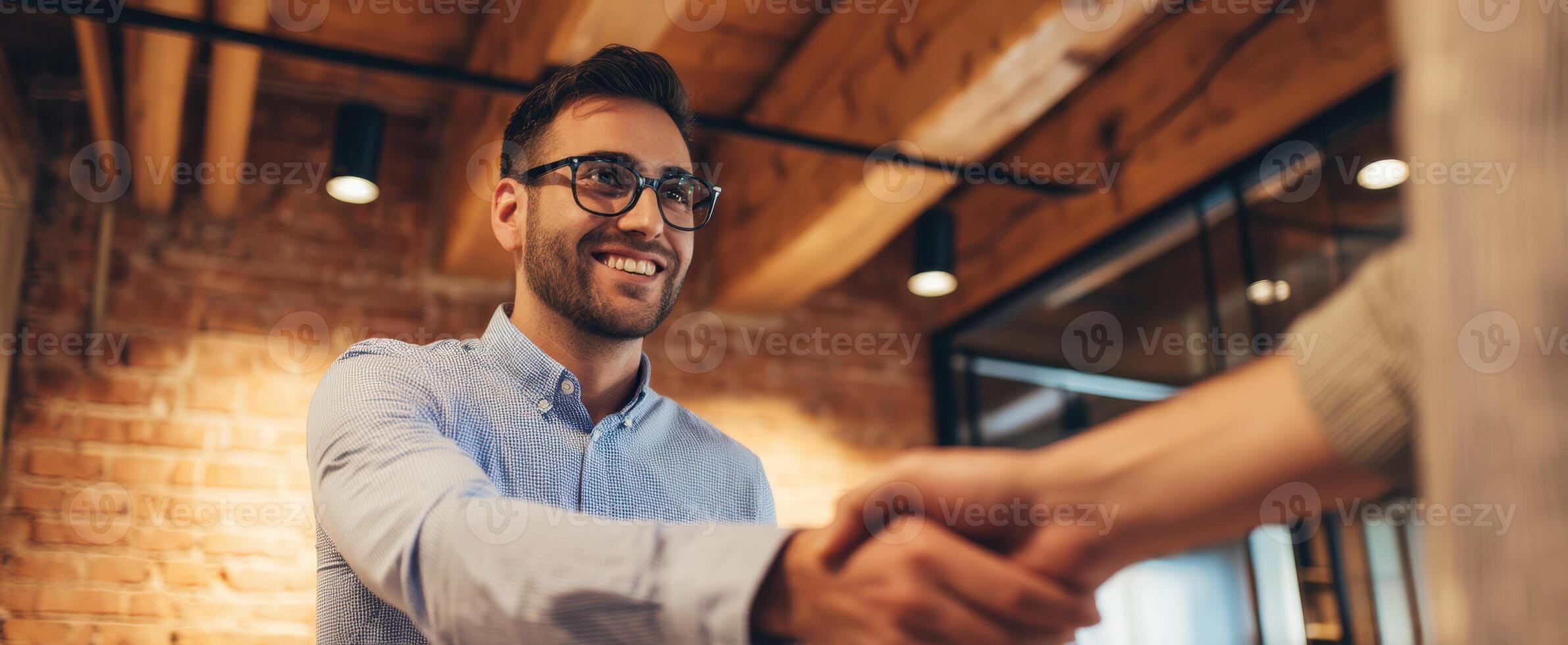 The businessman smiling during a handshake in a modern office setting. photo