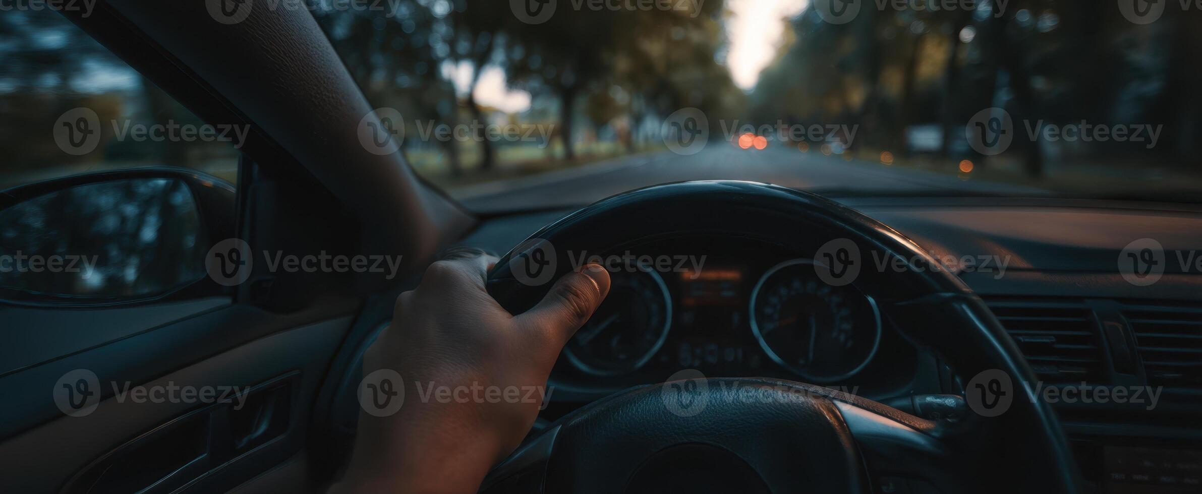 The hand gripping the steering wheel on an evening drive down a quiet road. photo