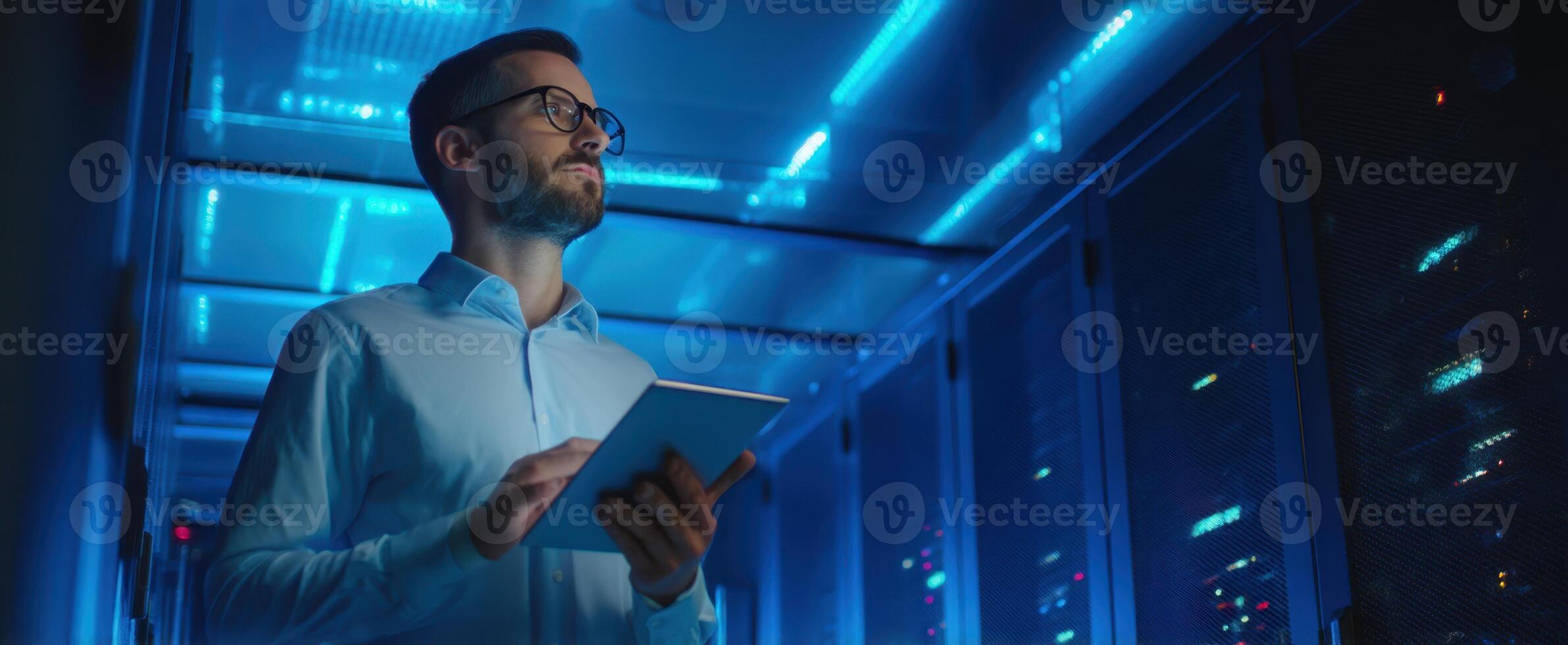 The man with a tablet in a futuristic server room illuminated by blue light. photo