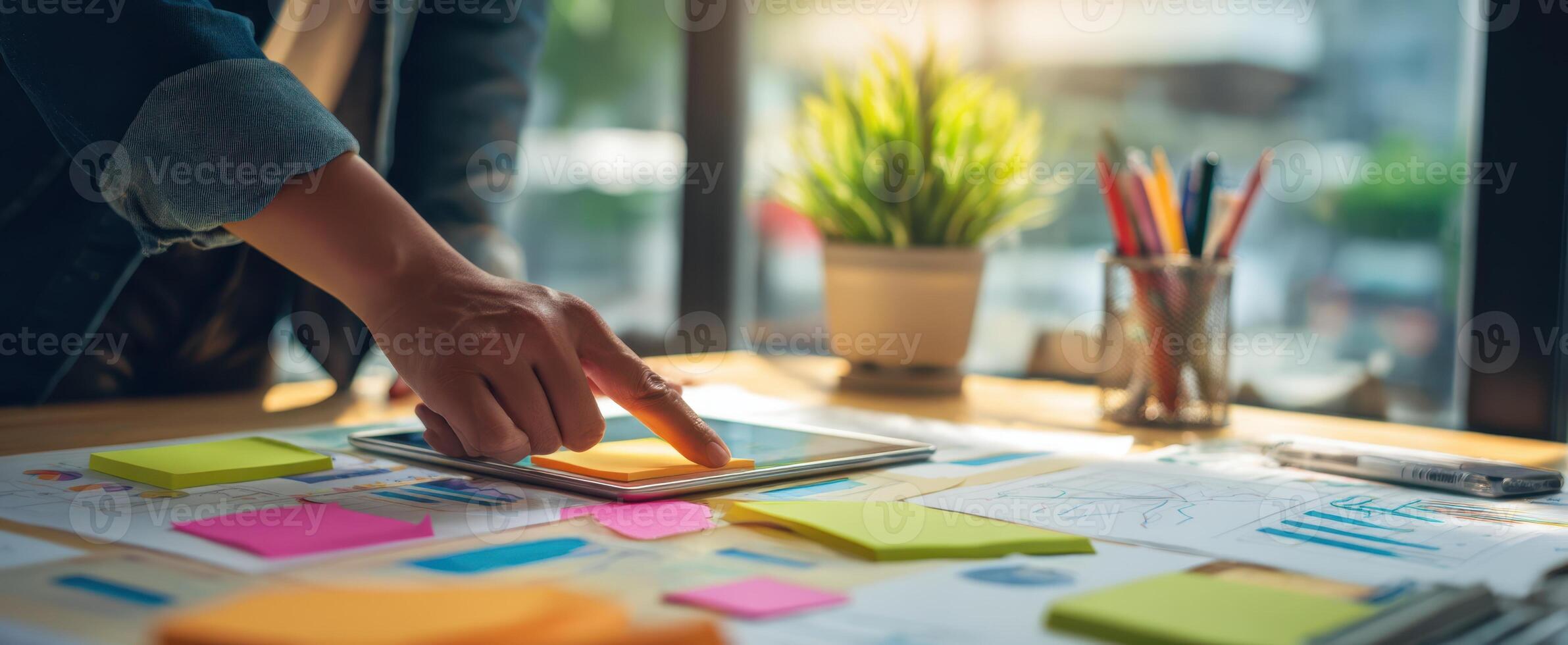 The creative workspace featuring a person interacting with a tablet and colorful notes. photo