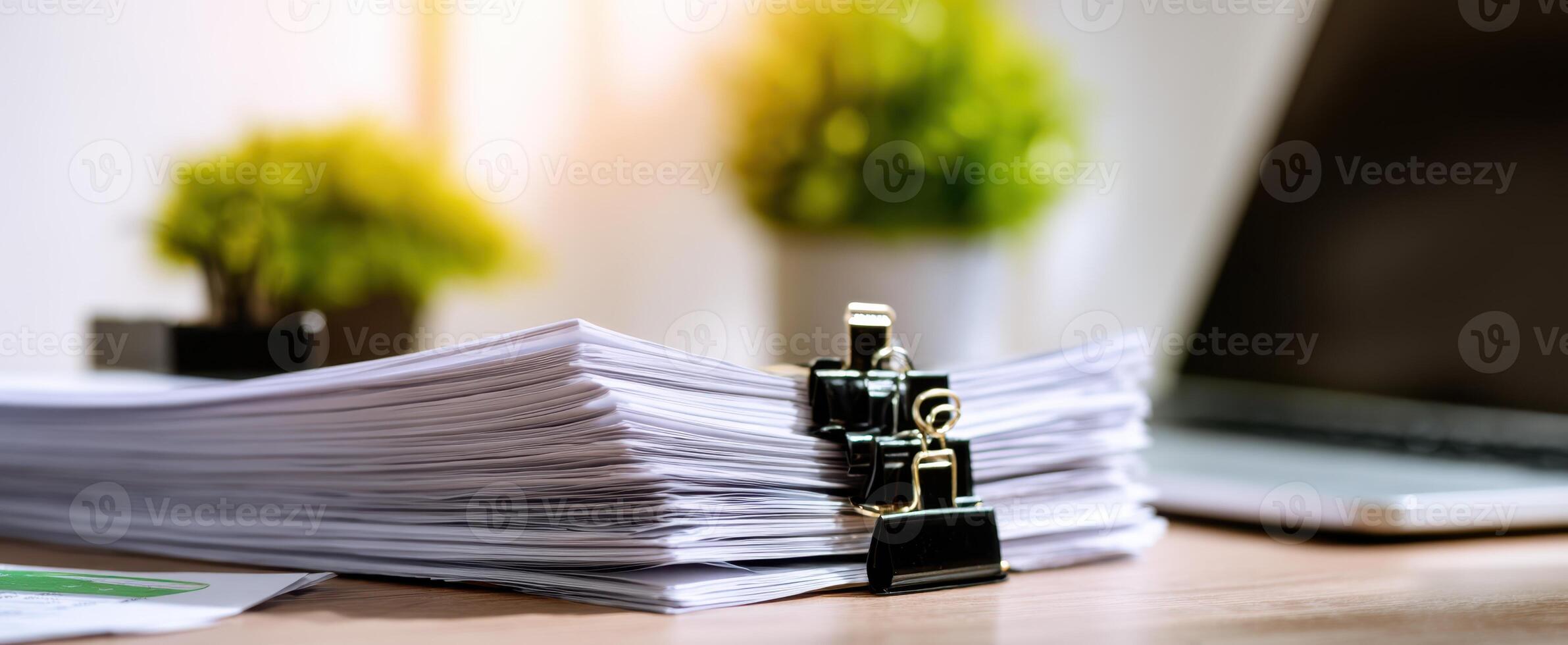 The organized stack of paperwork on a modern office desk with a laptop. photo