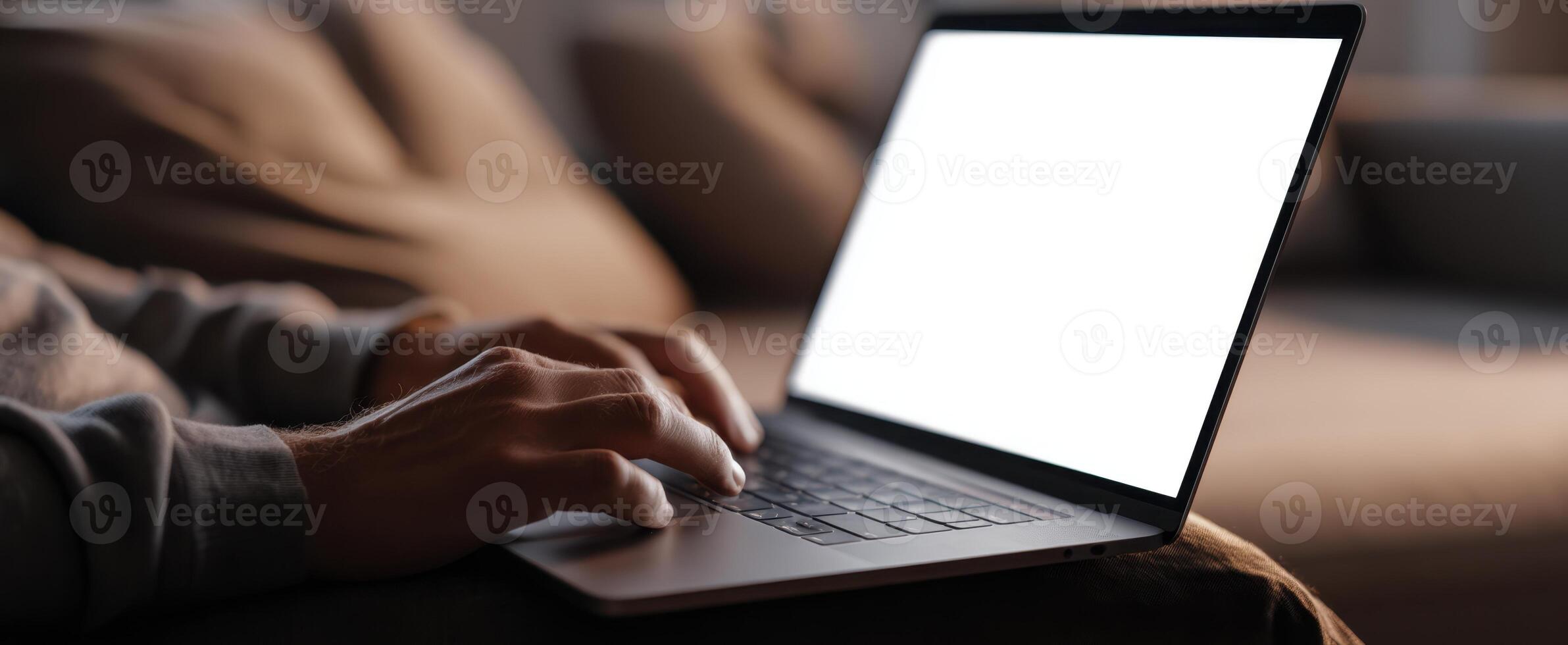 The laptop resting on a cozy couch with hands typing on the keyboard. photo