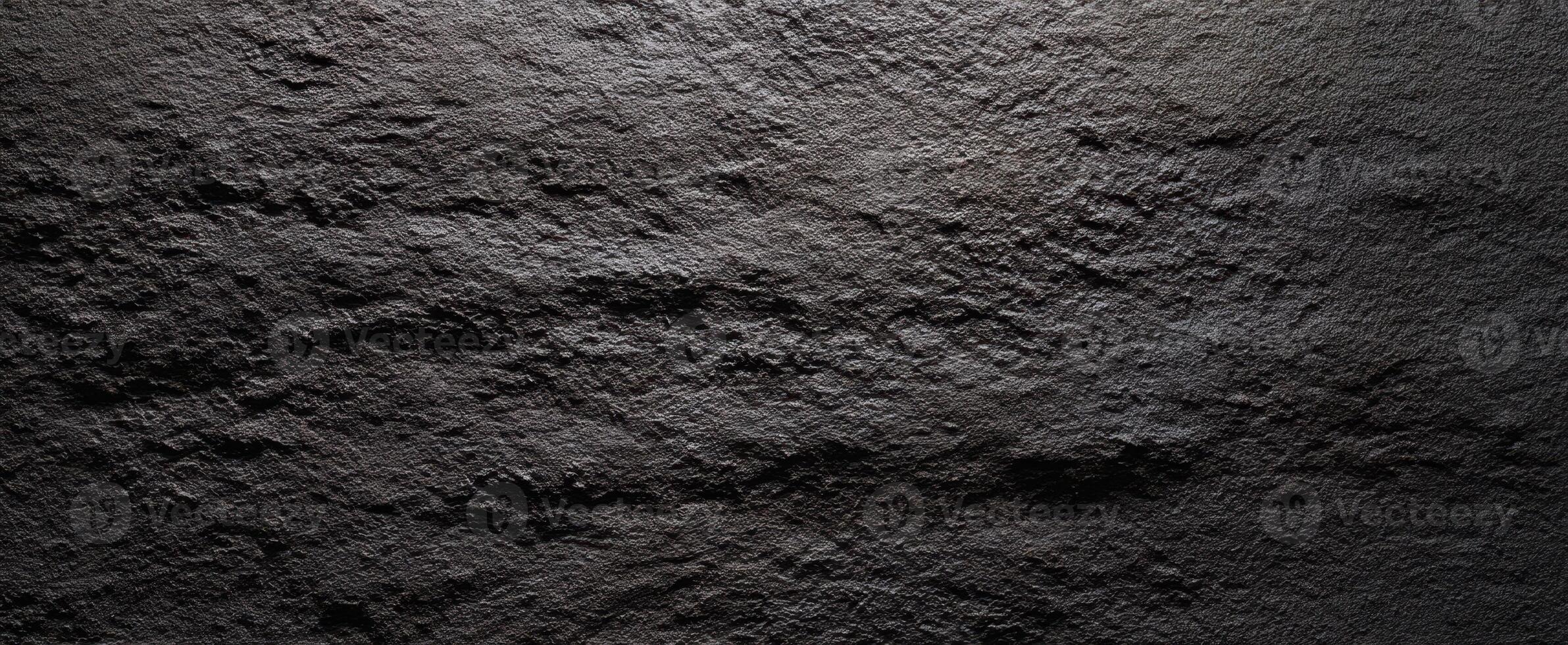 The textured black stone surface with intricate details and shadows. photo