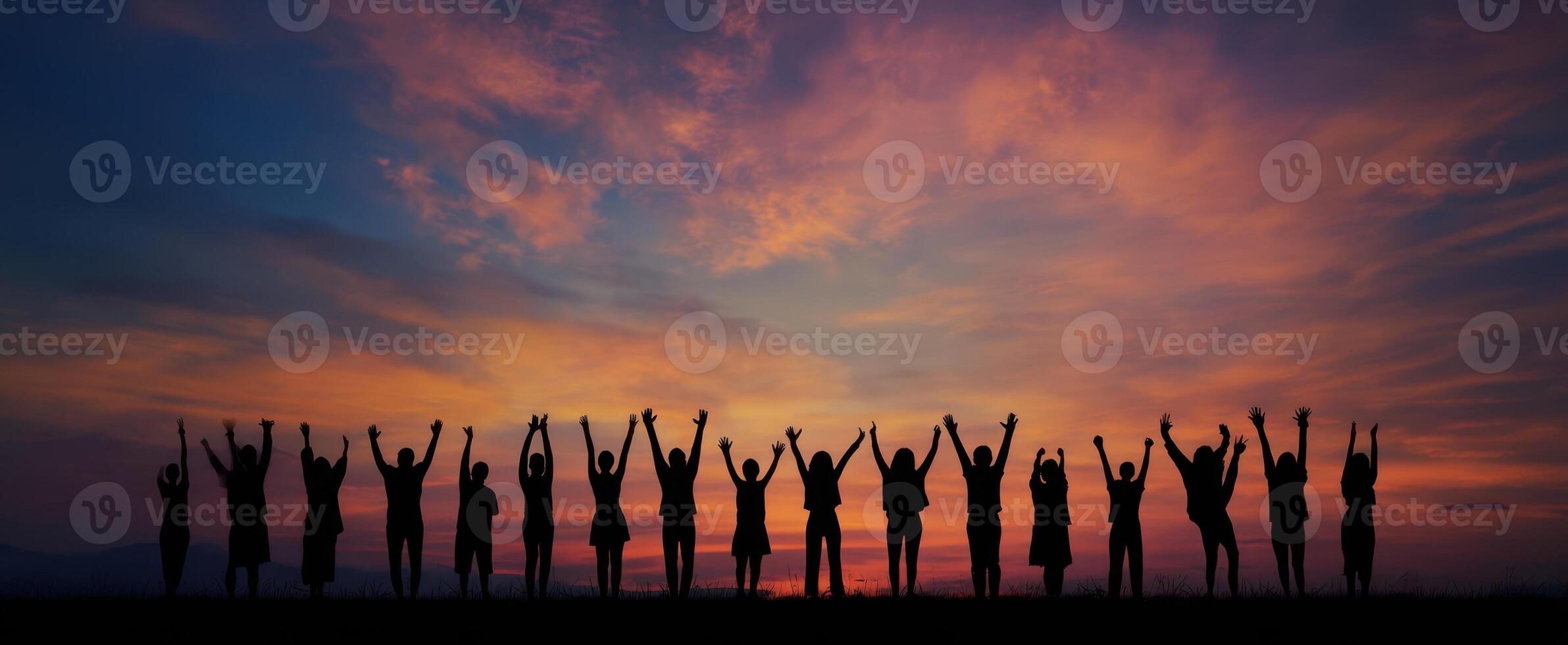 The silhouettes of a joyful group celebrating under a vibrant sunset sky. photo