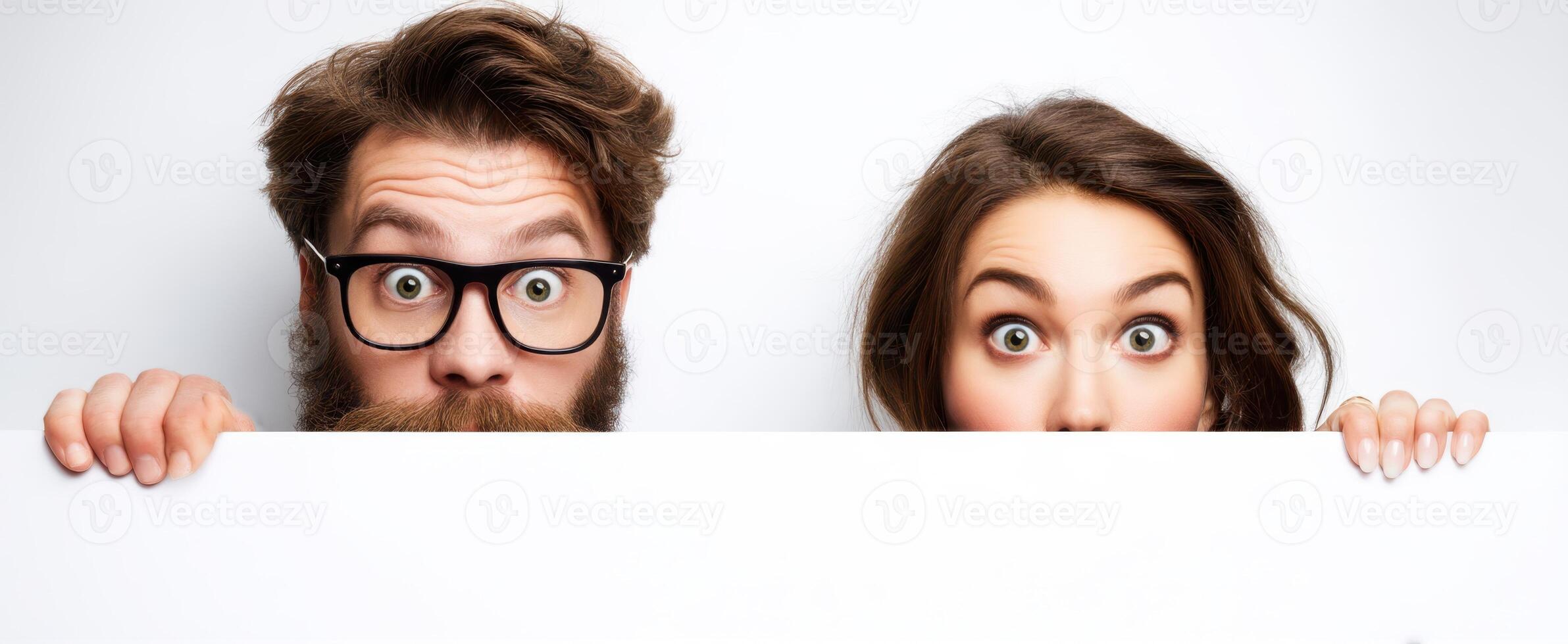 The surprised couple playfully holding a blank sign in a studio setting. photo