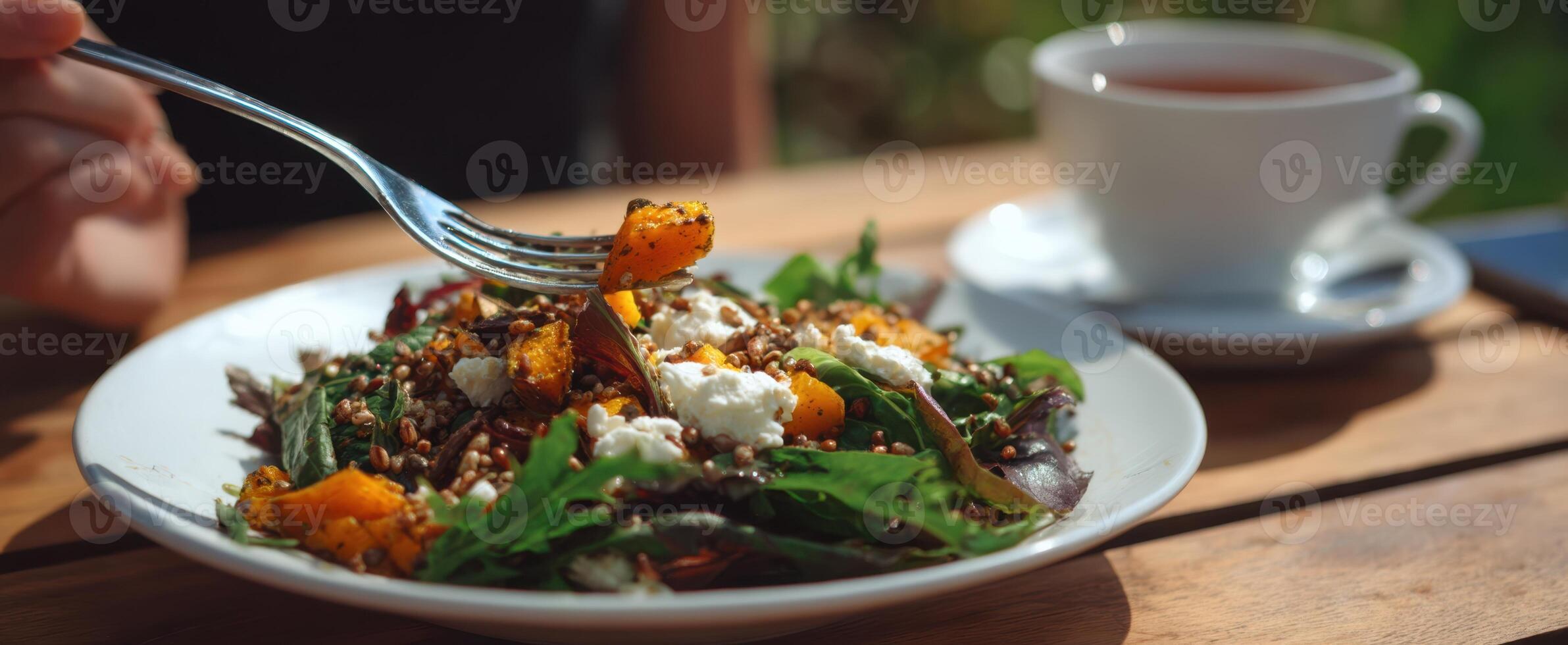 The vibrant salad with quinoa and pumpkin served alongside a cup of tea. photo