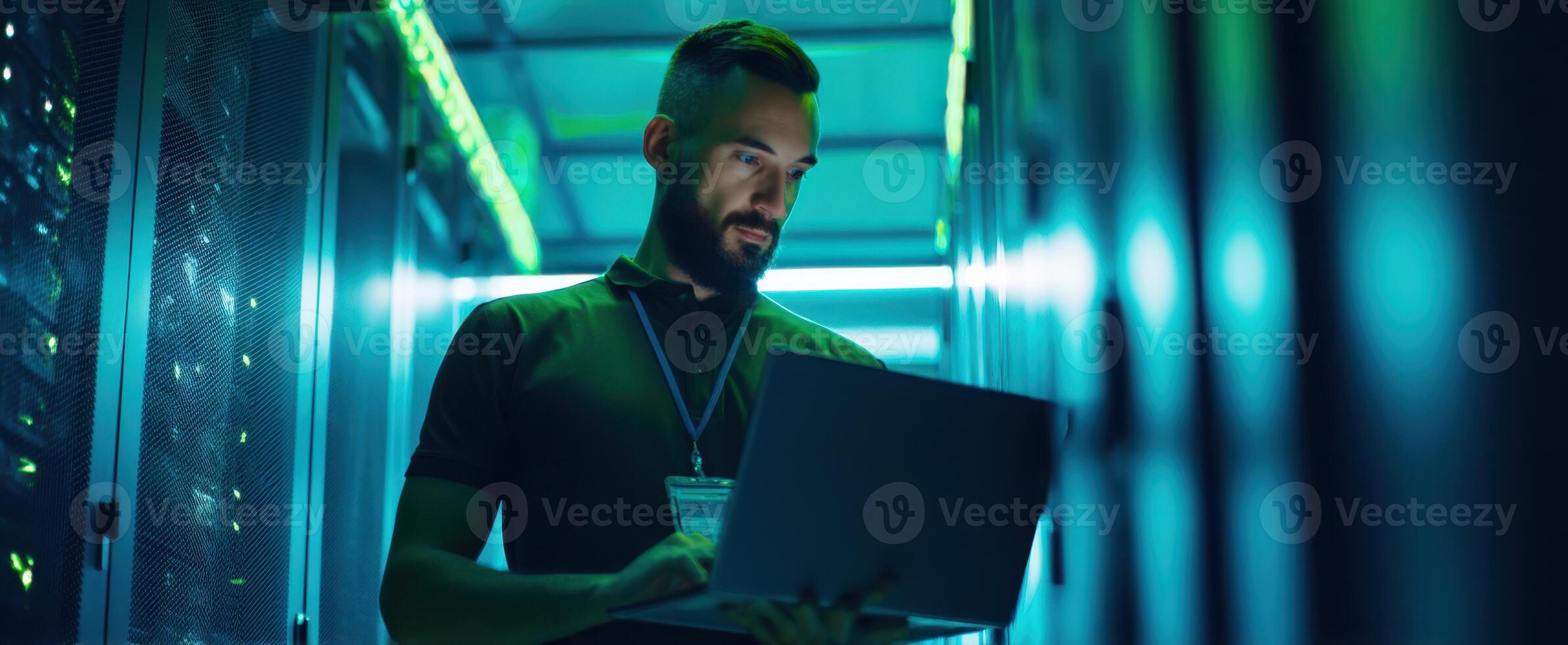 The focused IT professional working on a laptop in a server room. photo