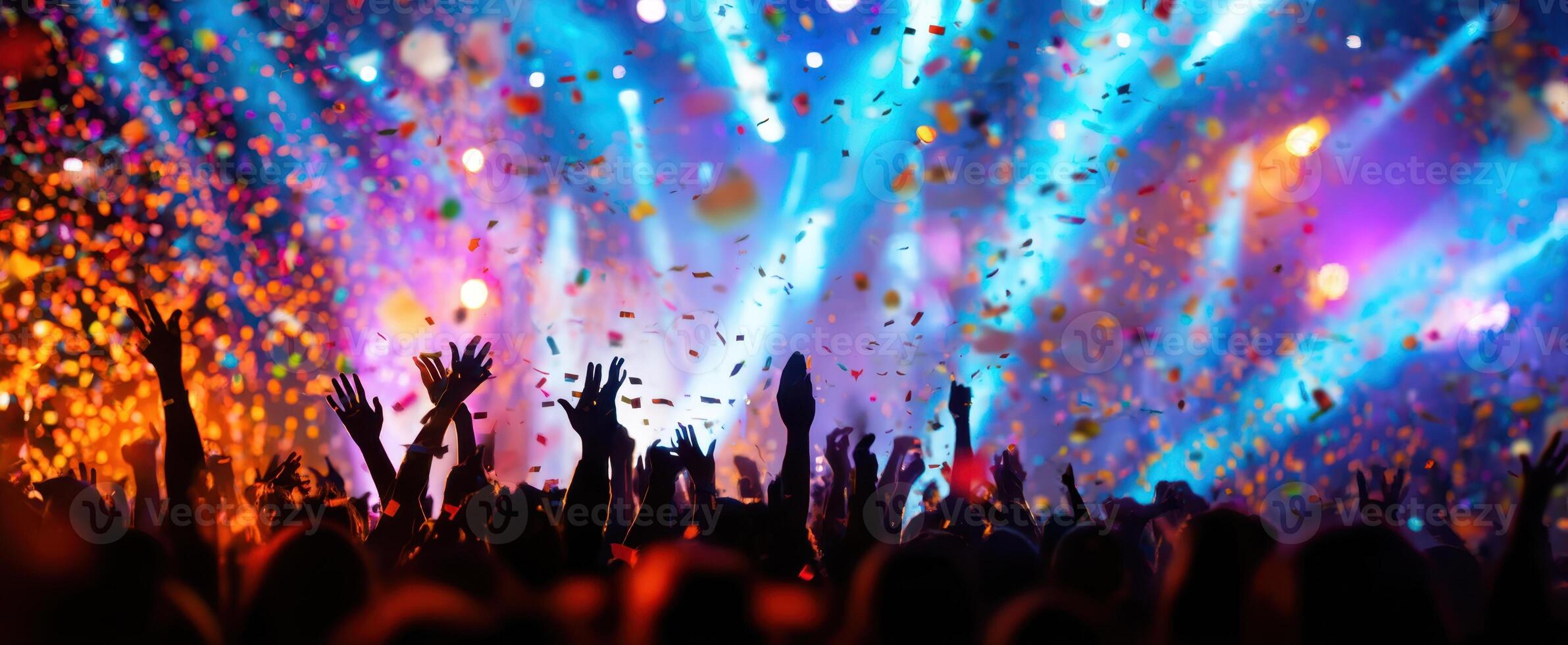 The vibrant crowd celebrating at a lively concert filled with colorful lights and confetti. photo