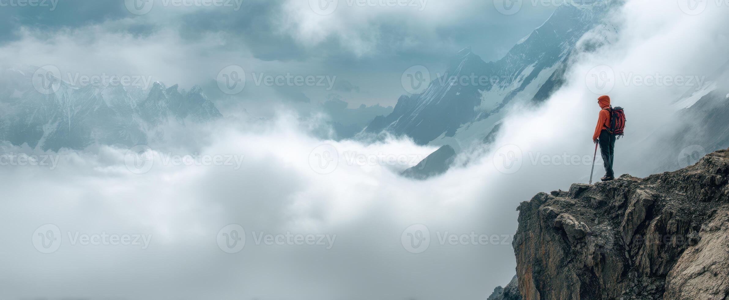 The adventurer standing on a cliff overlooking a breathtaking mountain landscape photo