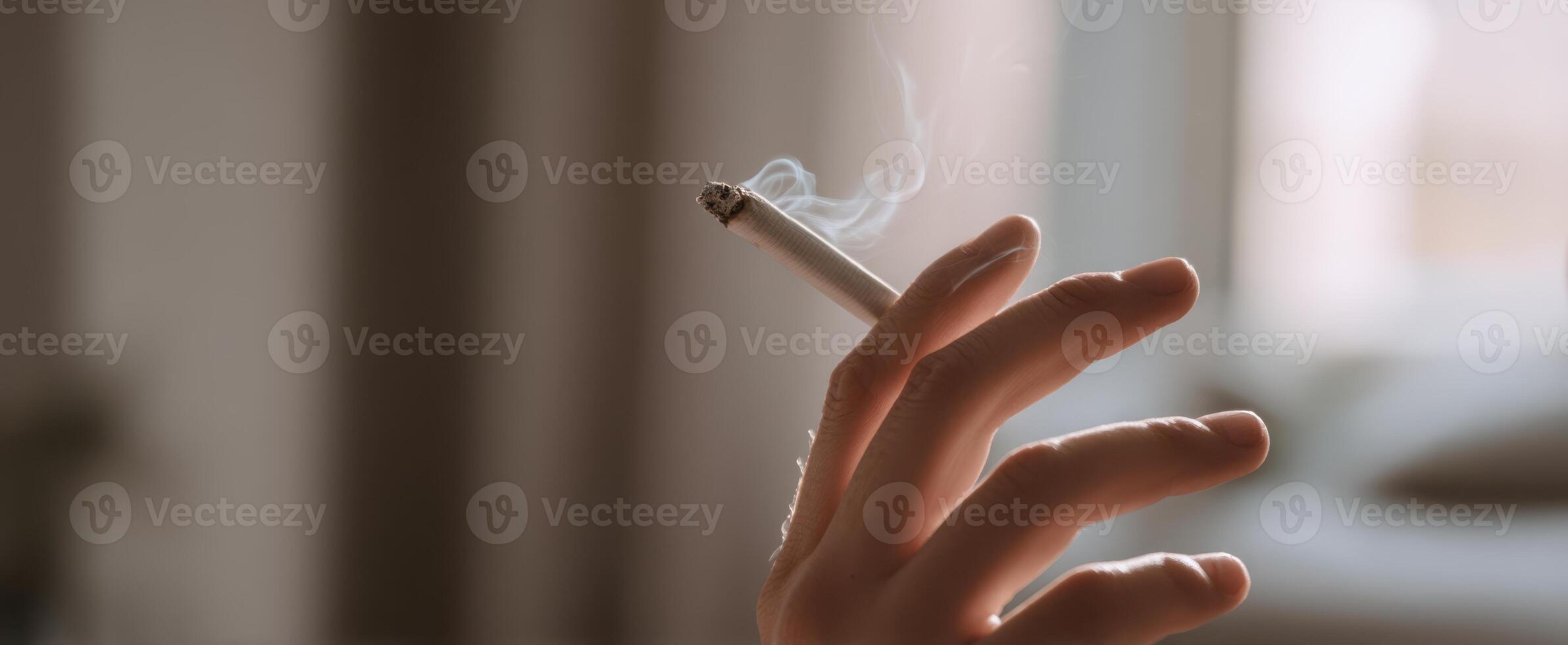 The hand holding a cigarette releasing soft smoke in a cozy atmosphere photo