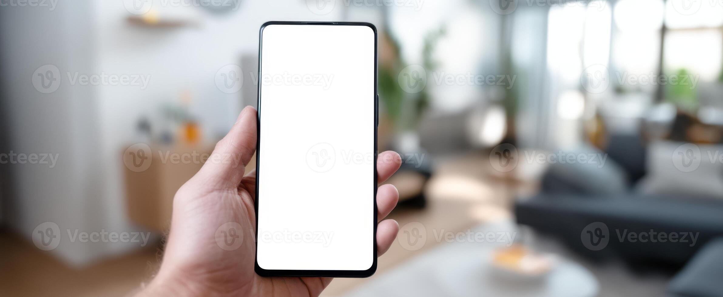 The smartphone held in hand on a blurred modern living room background. photo