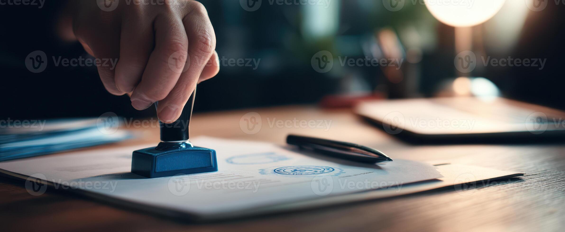 The hand using a blue stamp on an official document on a wooden desk photo