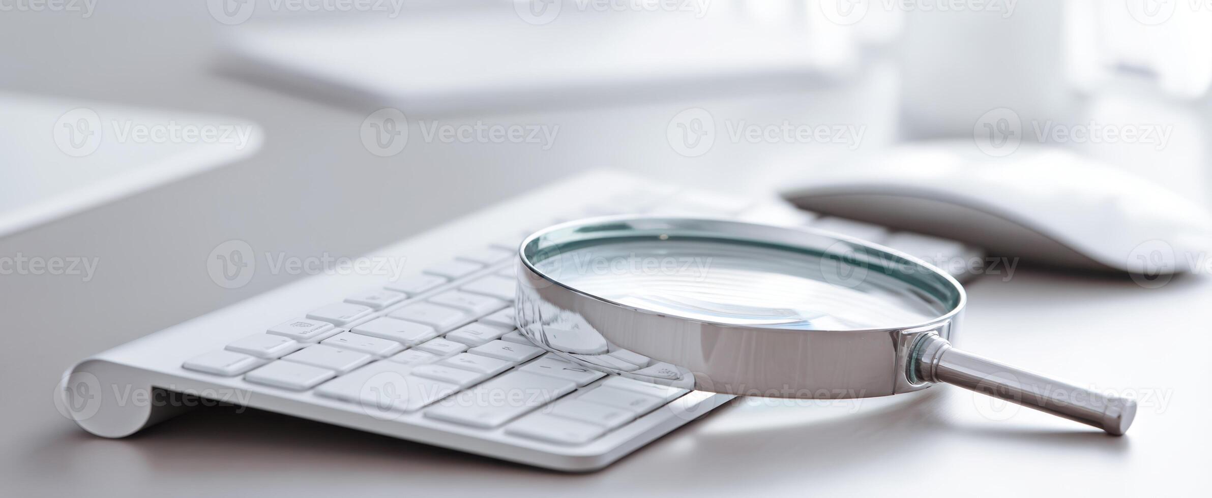 The magnifying glass resting on a modern keyboard in a sleek workspace. photo