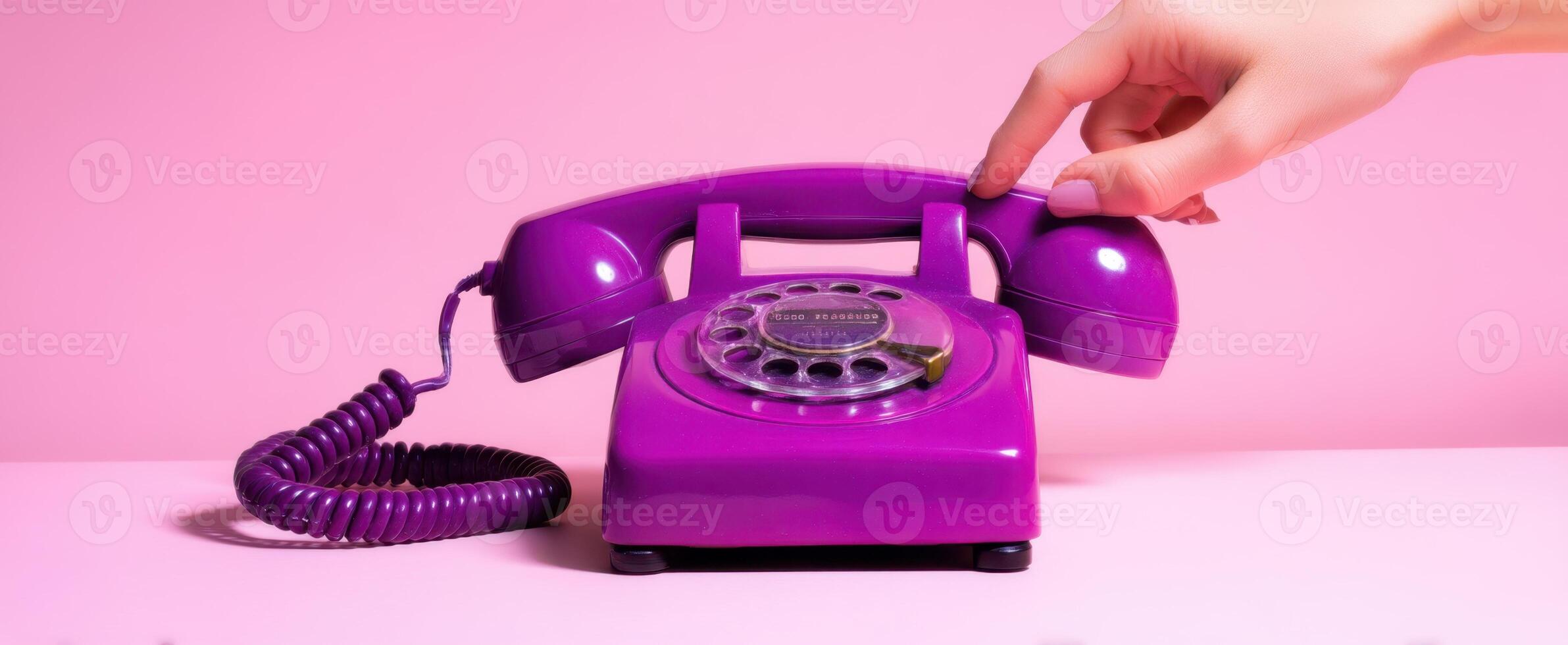 The stylish vintage purple telephone with a hand reaching to dial. photo