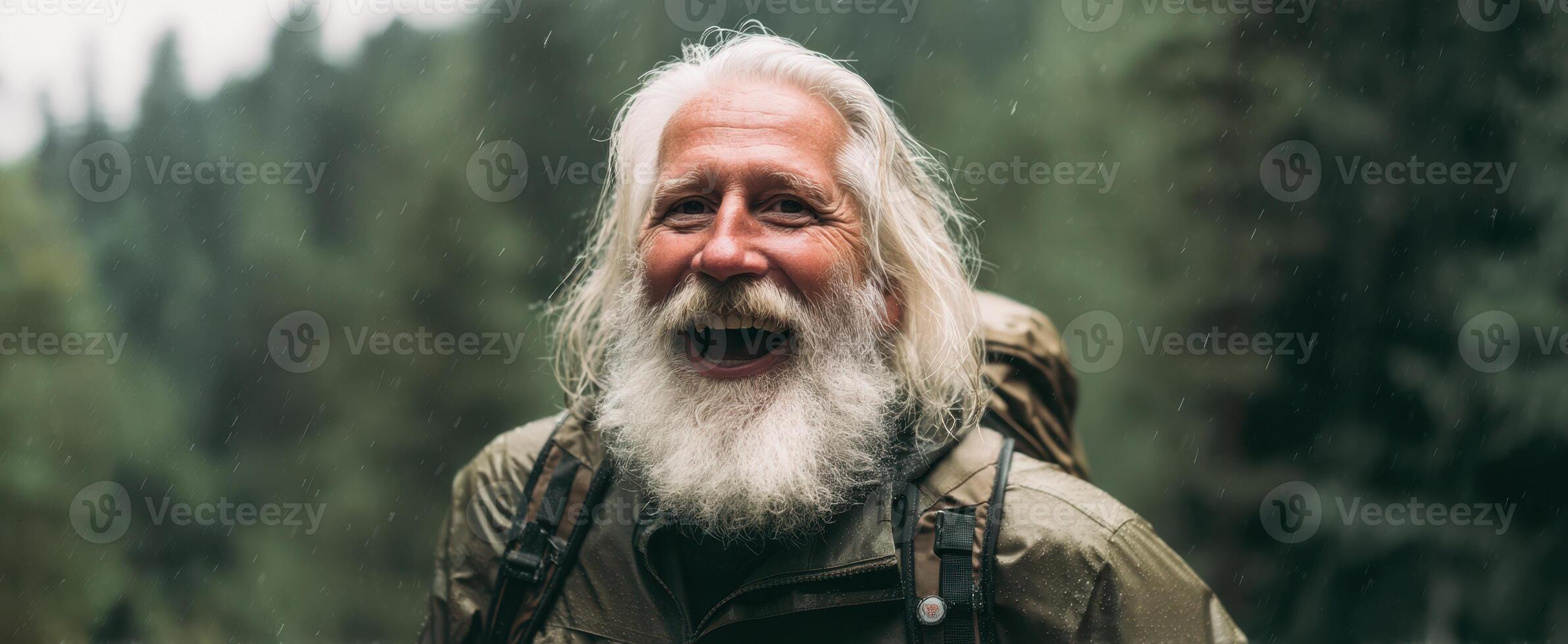 The joyful elderly man smiling in nature with a backpack amidst lush greenery. photo