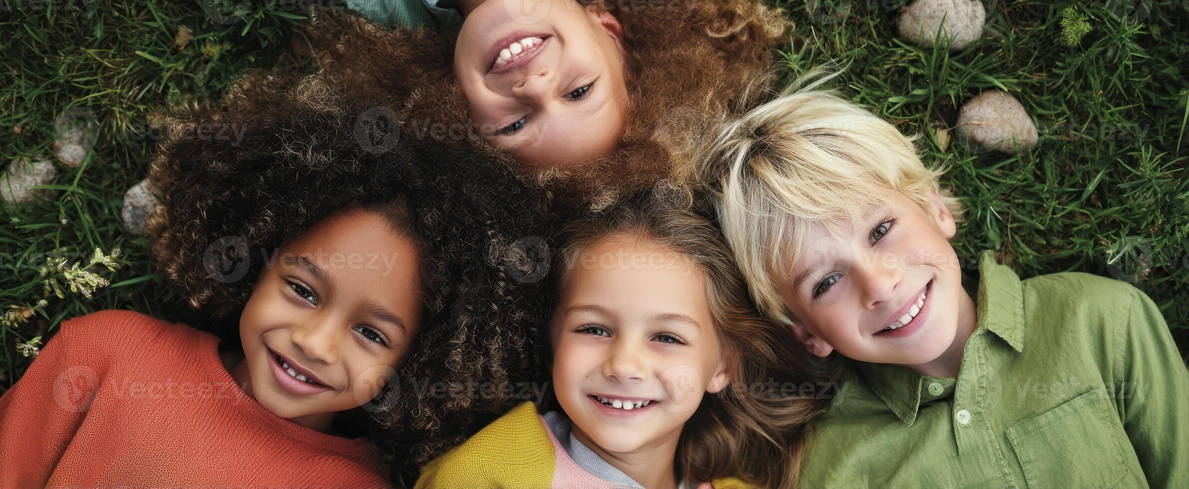 Four children are smiling and laying on the grass photo