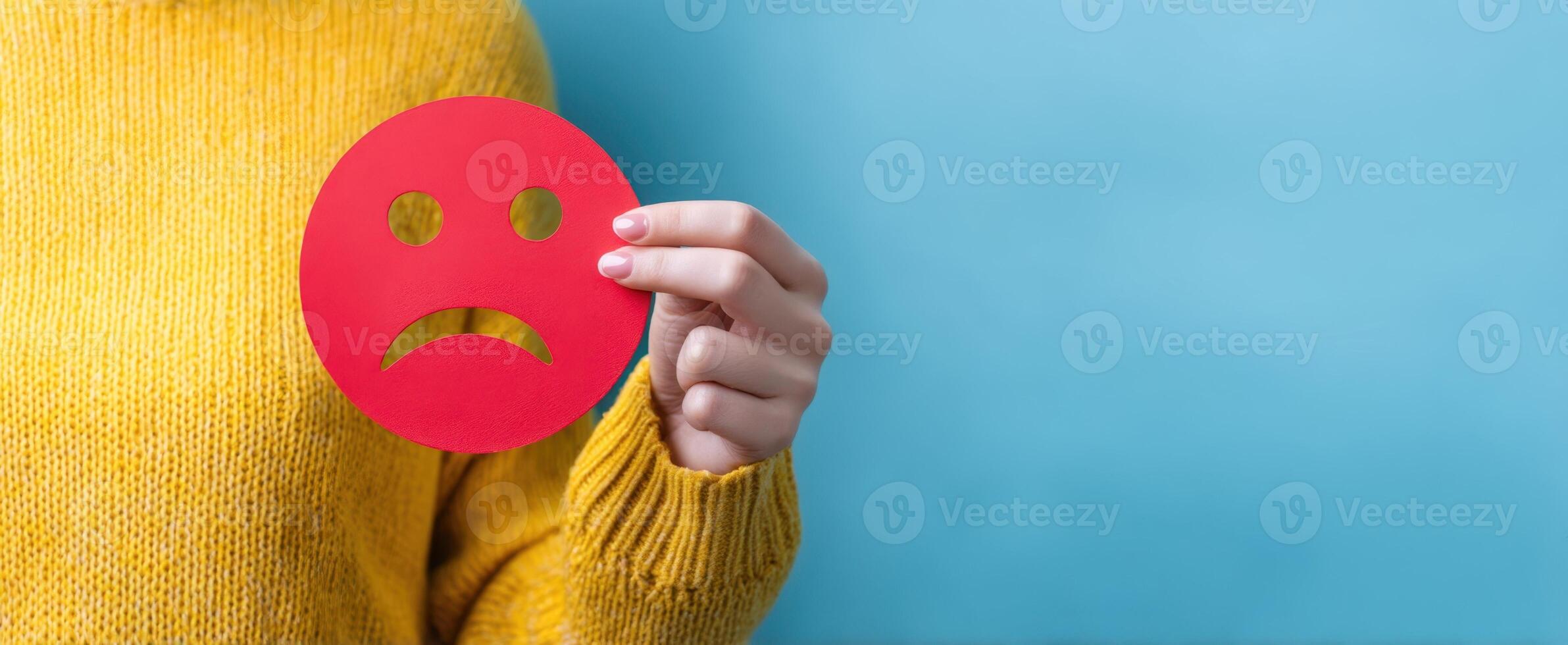 The emotion of sadness expressed through a hand-held red paper sad face photo