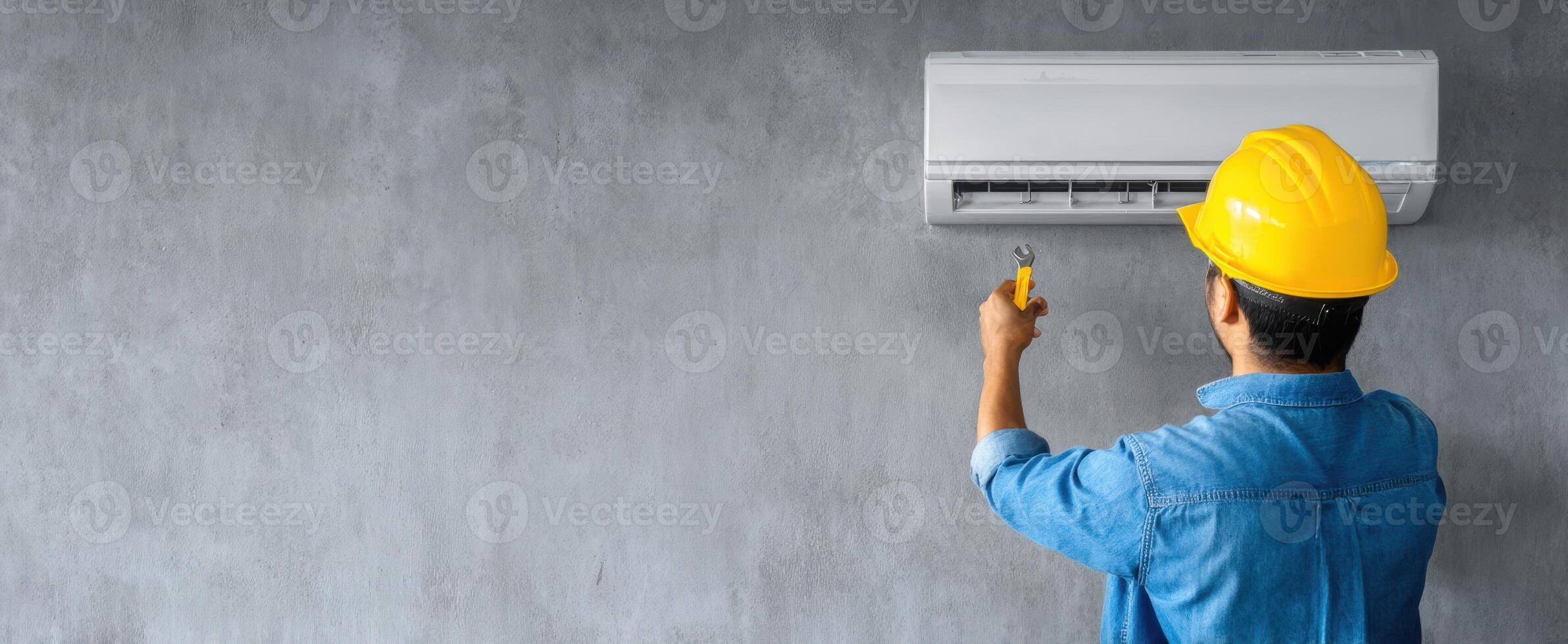 The technician installing an air conditioning unit on a concrete wall. photo