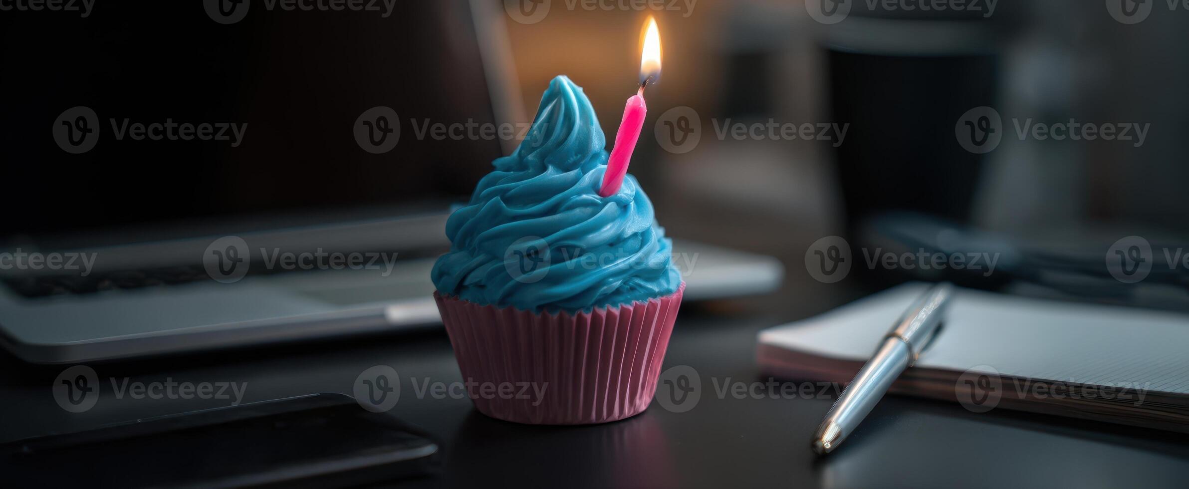 The colorful cupcake with a candle set on a stylish office desk. photo