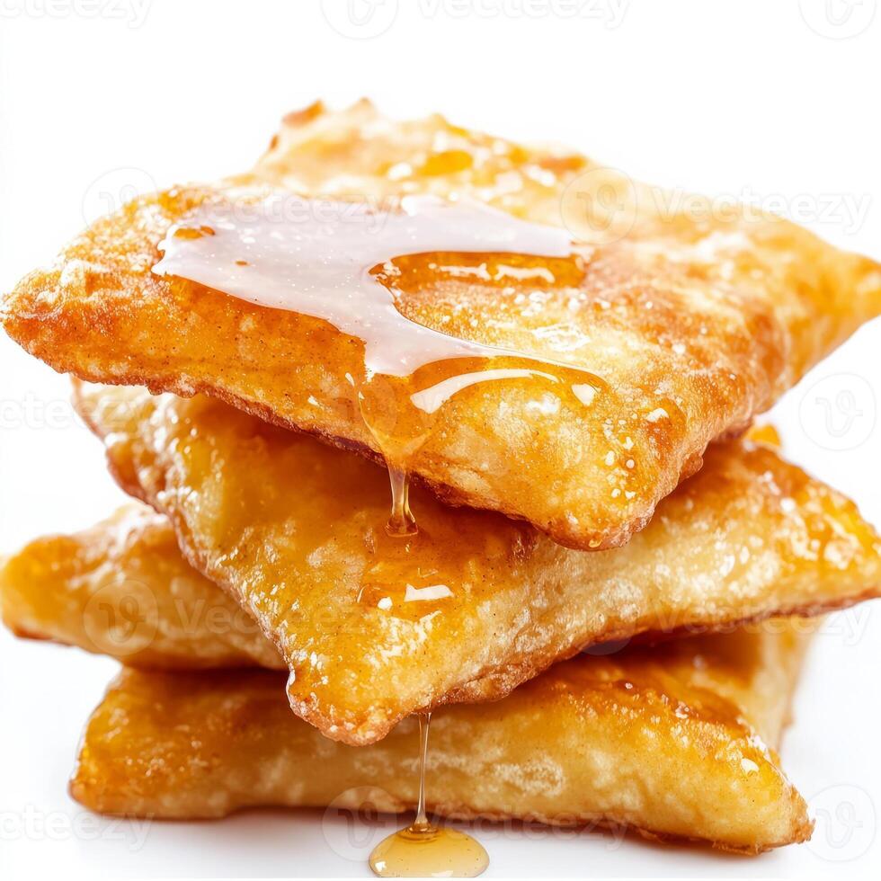A close-up of a stack of fluffy sopapillas, deep-fried pastries drizzled with honey and cinnamon, photo