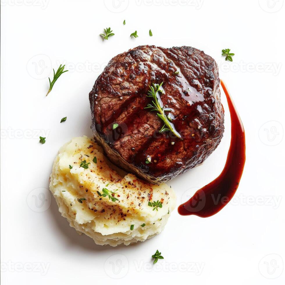 A perfectly seared filet mignon, cooked to a tender medium-rare, with a side of creamy mashed potatoes and a drizzle of red wine reduction sauce. A gourmet steakhouse dish. Isolated on clean white photo