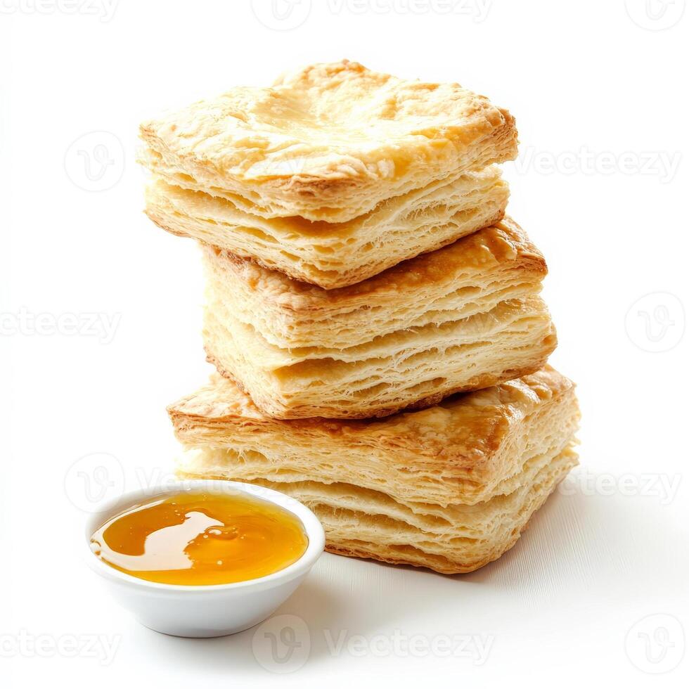 A stack of golden, buttery biscuits with flaky layers, served with a side of honey butter. The biscuits have a slightly crisp exterior and a soft, tender interior. Isolated on clean white background photo