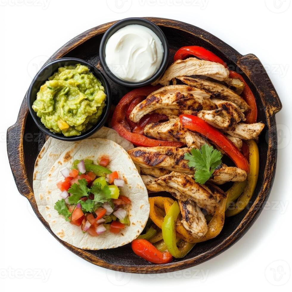 A sizzling hot fajita platter with grilled chicken, bell peppers, and onions, served with warm flour tortillas, guacamole, salsa, and sour cream. Isolated on clean white background photo