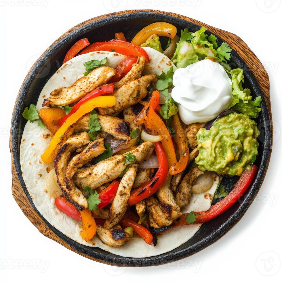 A sizzling plate of fajitas with grilled chicken, bell peppers, onions, and warm flour tortillas, served with guacamole and sour cream. A Mexican classic. Isolated on clean white background photo