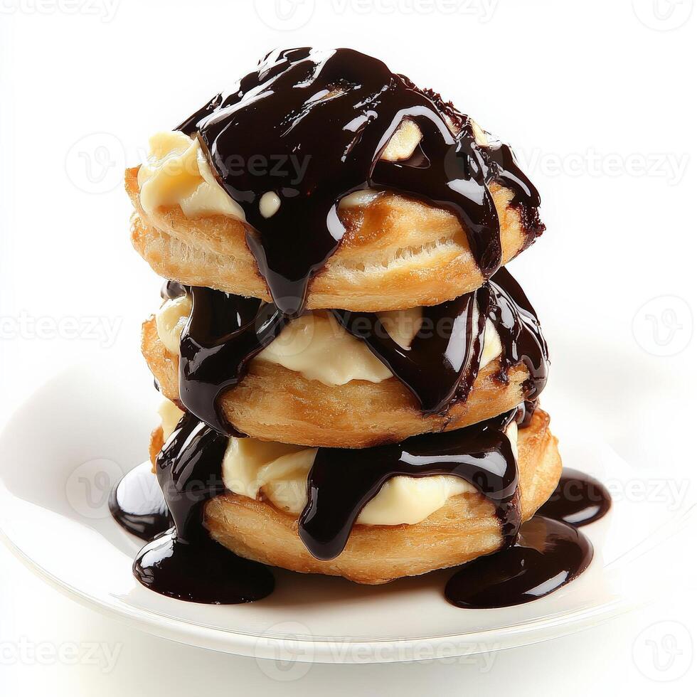 A close-up of a profiterole au chocolat, a cream puff filled with vanilla pastry cream and topped with chocolate sauce, arranged in a stack on a plate, showcasing the light and airy pastry and the rich chocolate, isolated on clean white background. photo