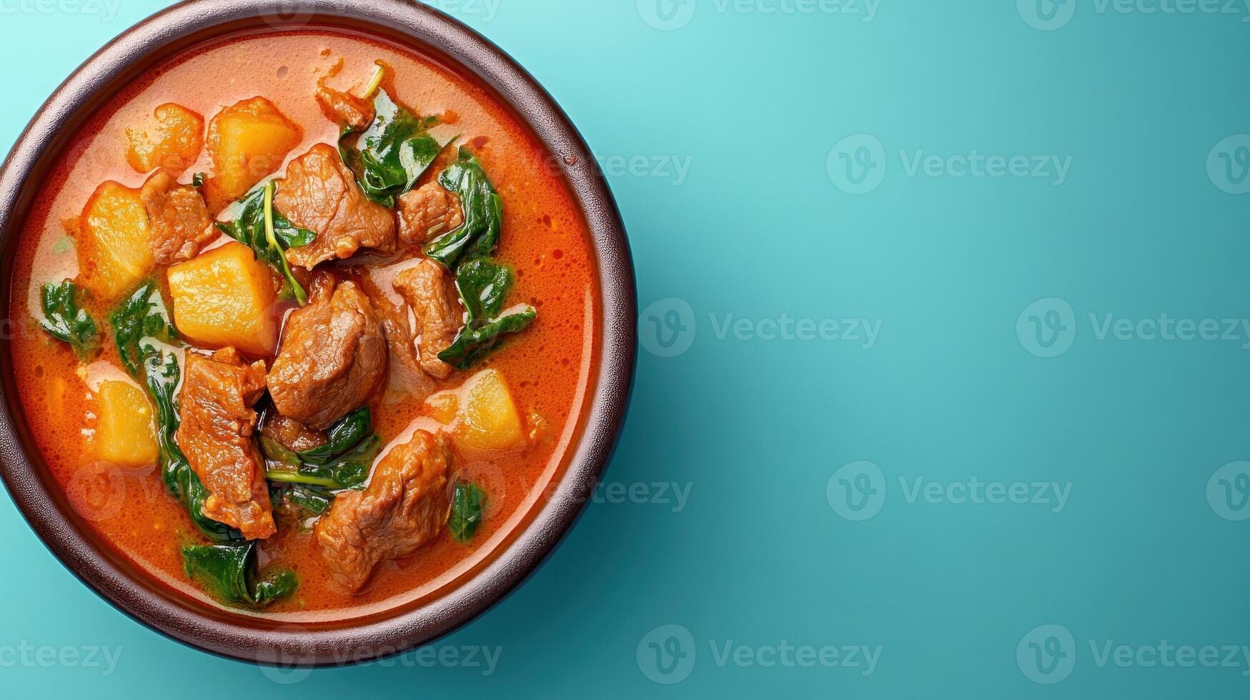 Beef, potatoes and spinach stew in bowl, on teal background. Healthy meal concept photo