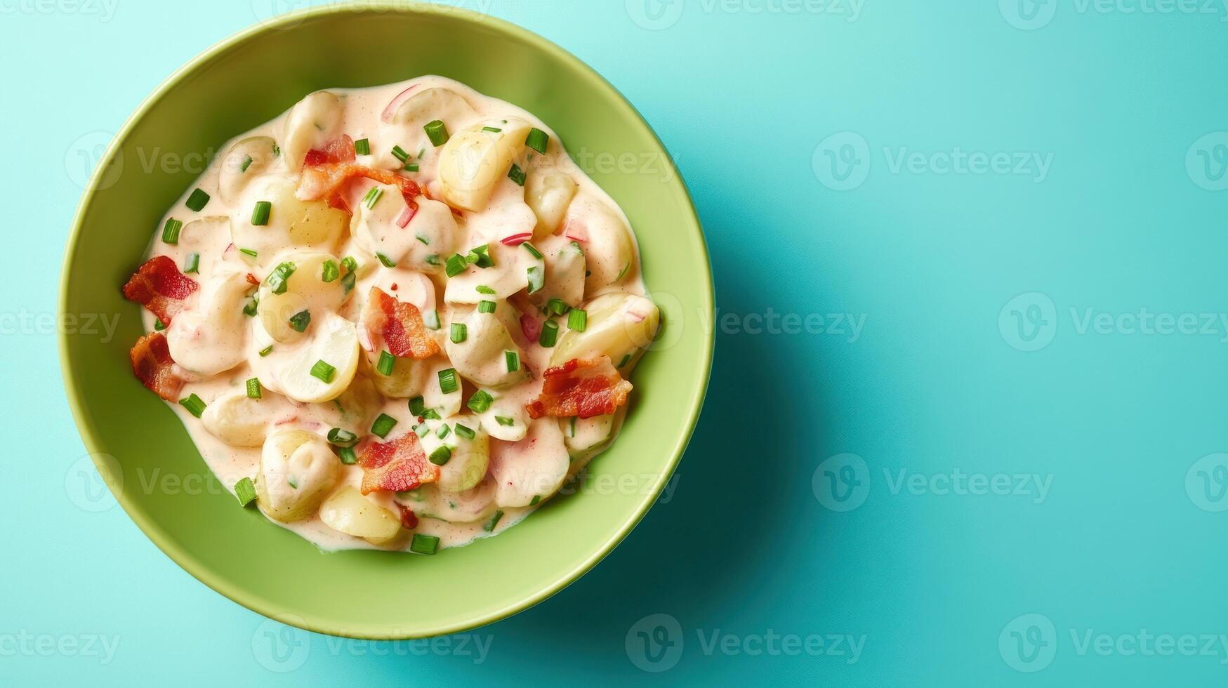 Bowl of potato salad with bacon and chives on blue background, ready to eat as side dish photo
